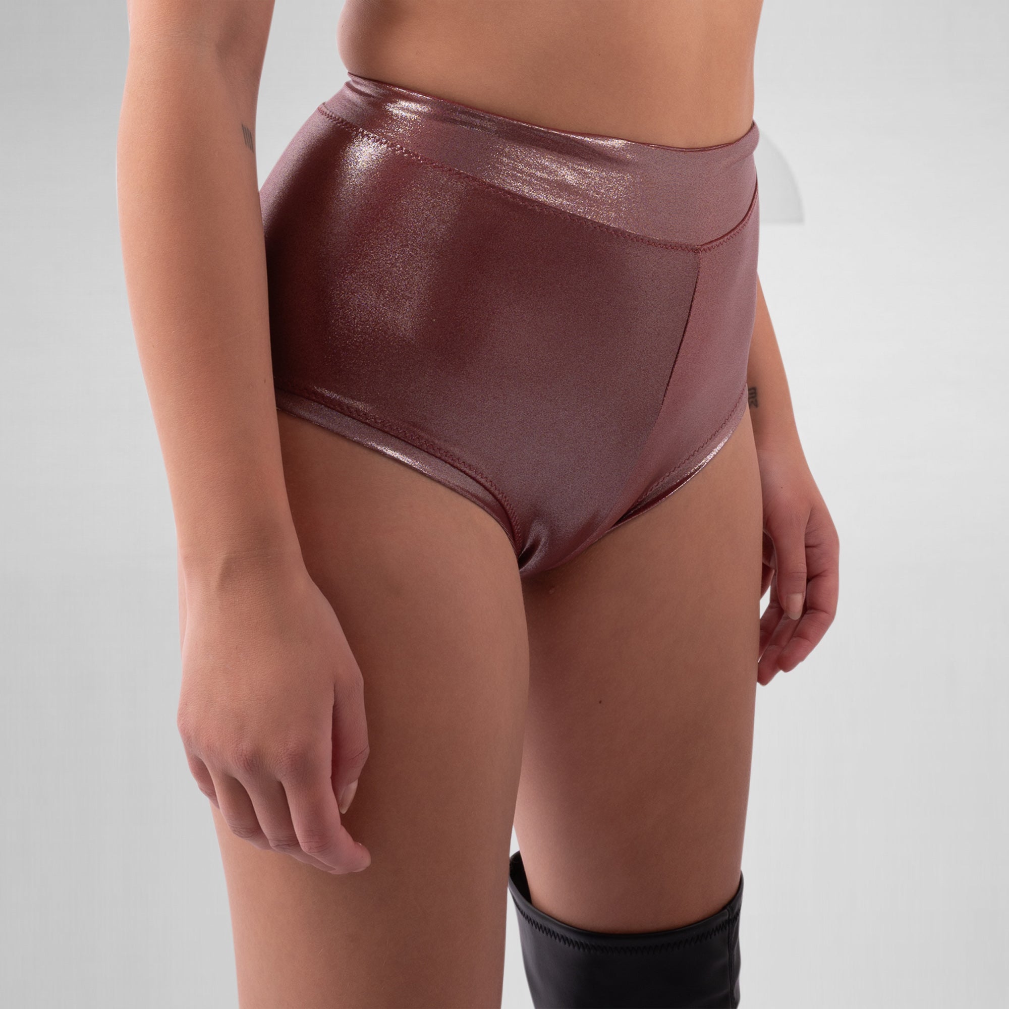 Person wearing shiny maroon high-waisted underwear on a plain background