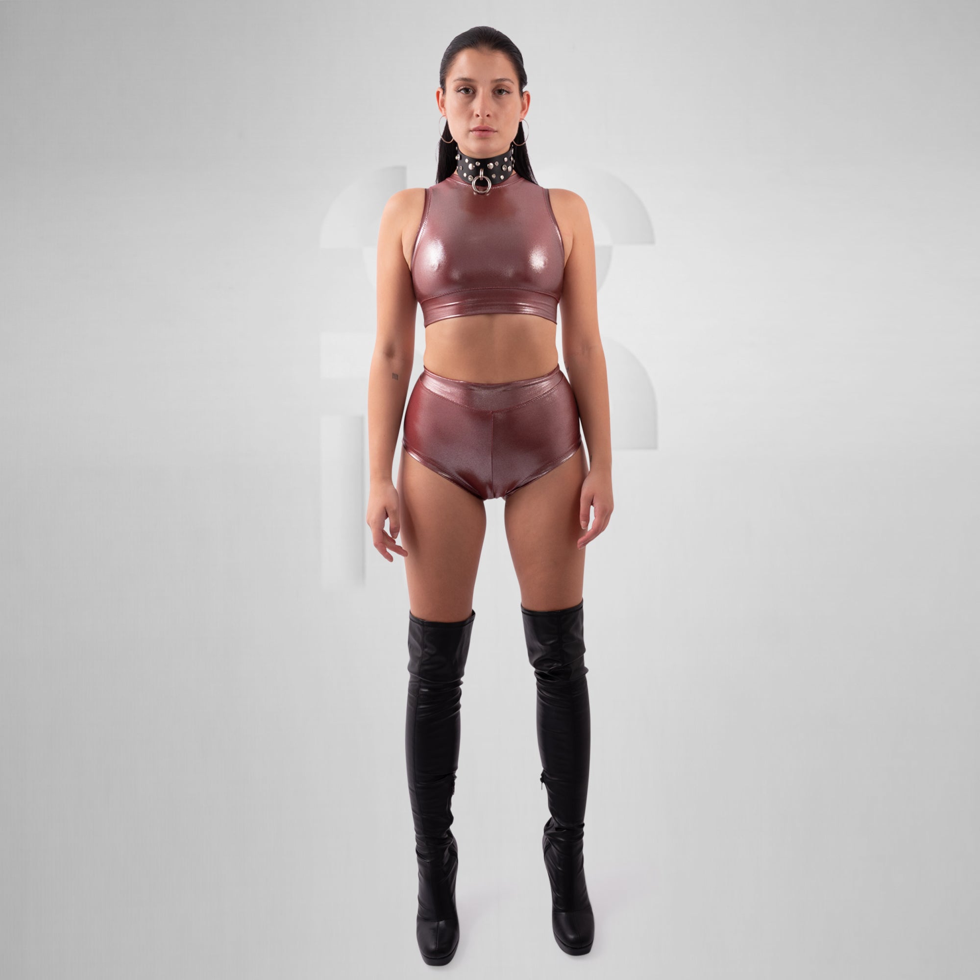 Person wearing a shiny maroon outfit with black knee-high boots on a white background