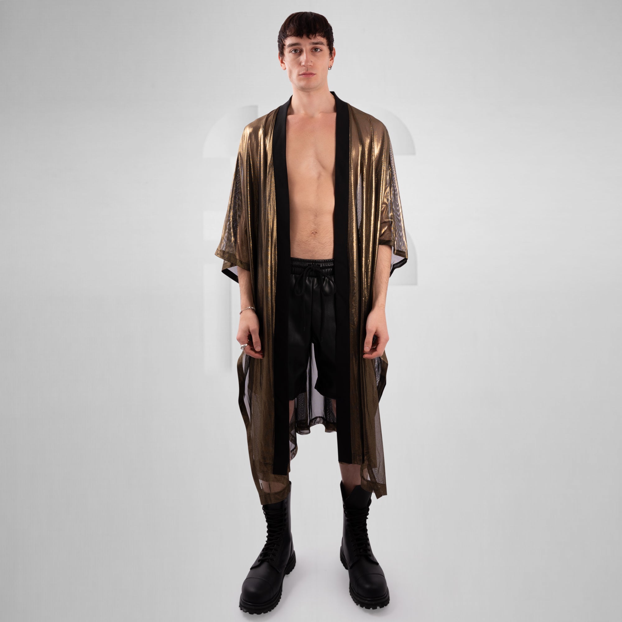 Man wearing a metallic gold robe over black pants on a white background