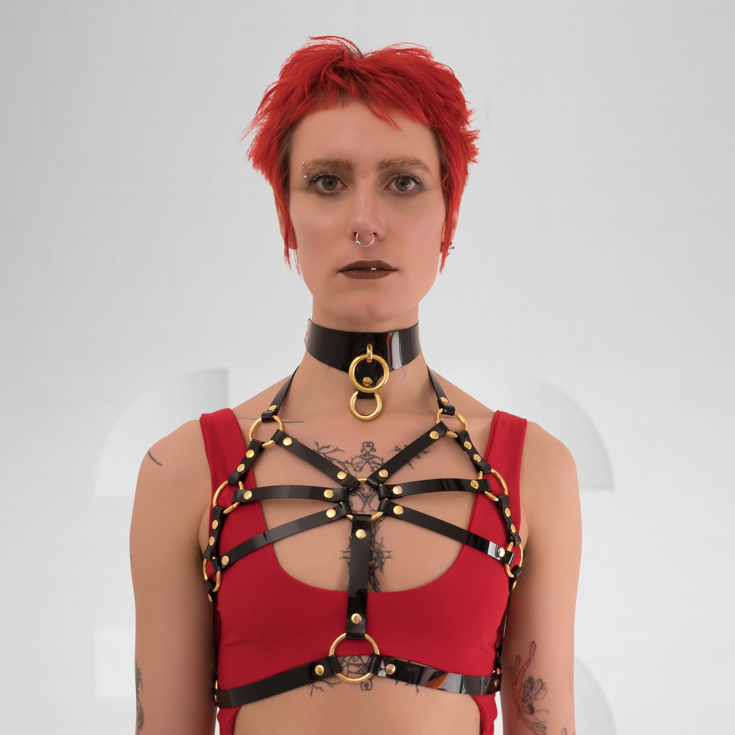 A back view of the Harness Top in Black PVC from Miss Overdose, featuring striking golden or silver rings. This edgy and stylish harness captures a kinky aesthetic, making it ideal for events, techno clubs, or festivals, while also ensuring a comfortable fit.