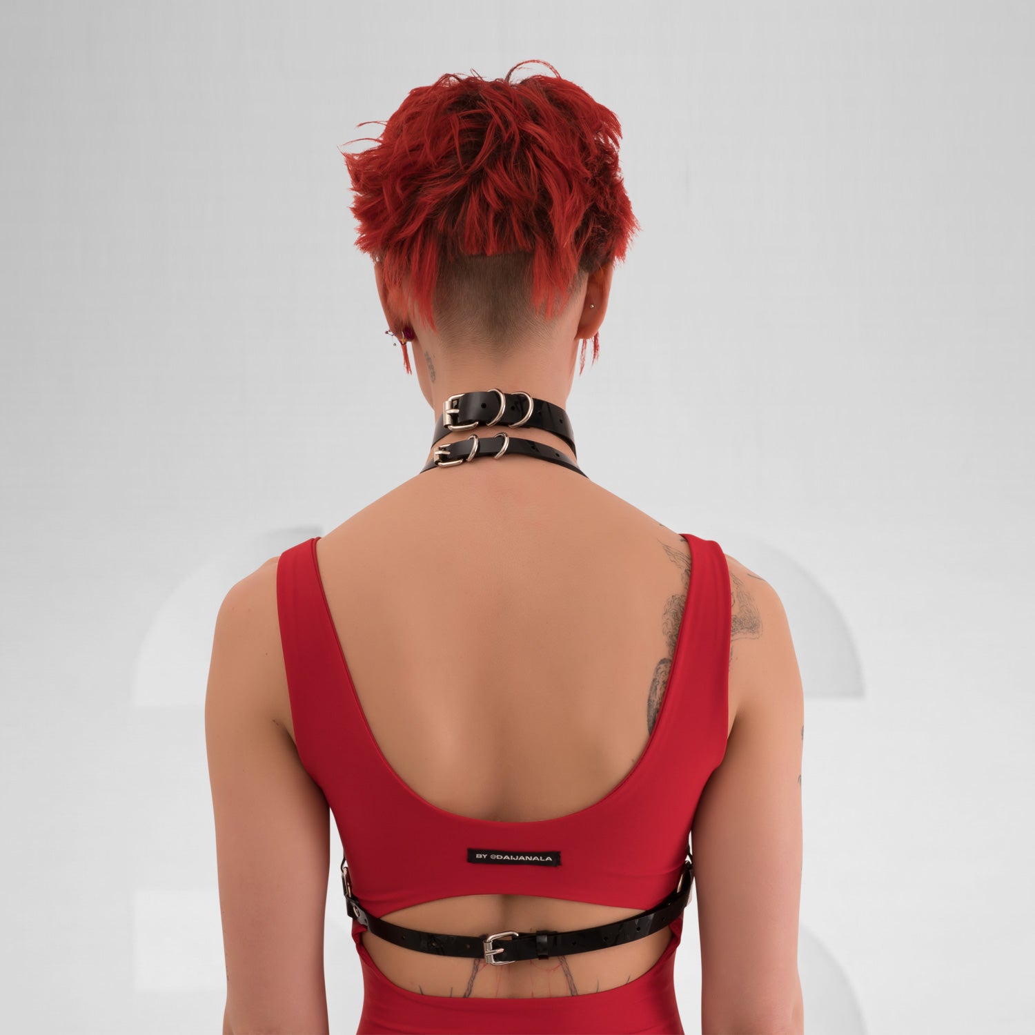 A back view of the Harness Top in Black PVC from Miss Overdose, featuring striking golden or silver rings. This edgy and stylish harness captures a kinky aesthetic, making it ideal for events, techno clubs, or festivals, while also ensuring a comfortable fit.