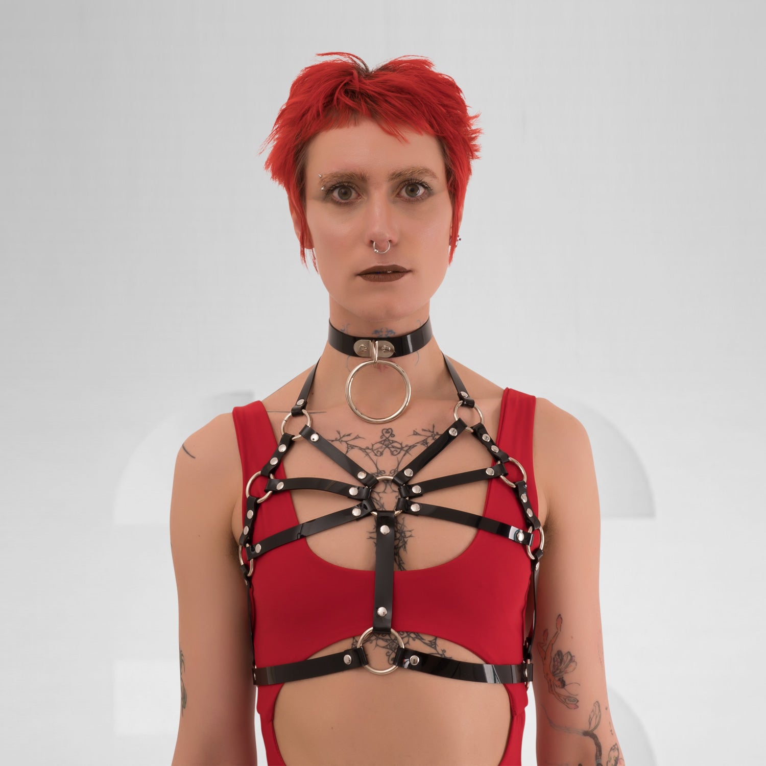 A back view of the Harness Top in Black PVC from Miss Overdose, featuring striking golden or silver rings. This edgy and stylish harness captures a kinky aesthetic, making it ideal for events, techno clubs, or festivals, while also ensuring a comfortable fit.