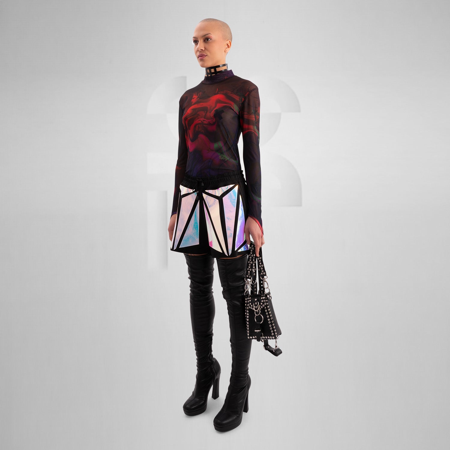Close-up of a model wearing black shorts with striking holographic geometric panels, reflecting iridescent colors. Paired with a sheer long-sleeve top and thigh-high black leather boots, this futuristic and edgy look is perfect for festival, rave, and avant-garde fashion.