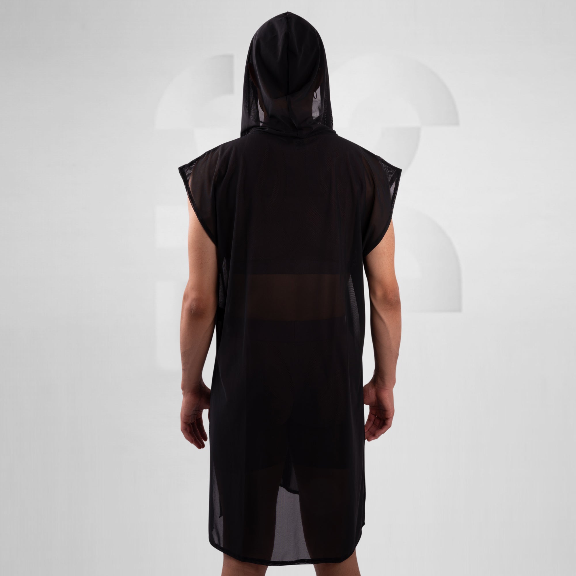 Person wearing a black sleeveless hooded garment on a white background