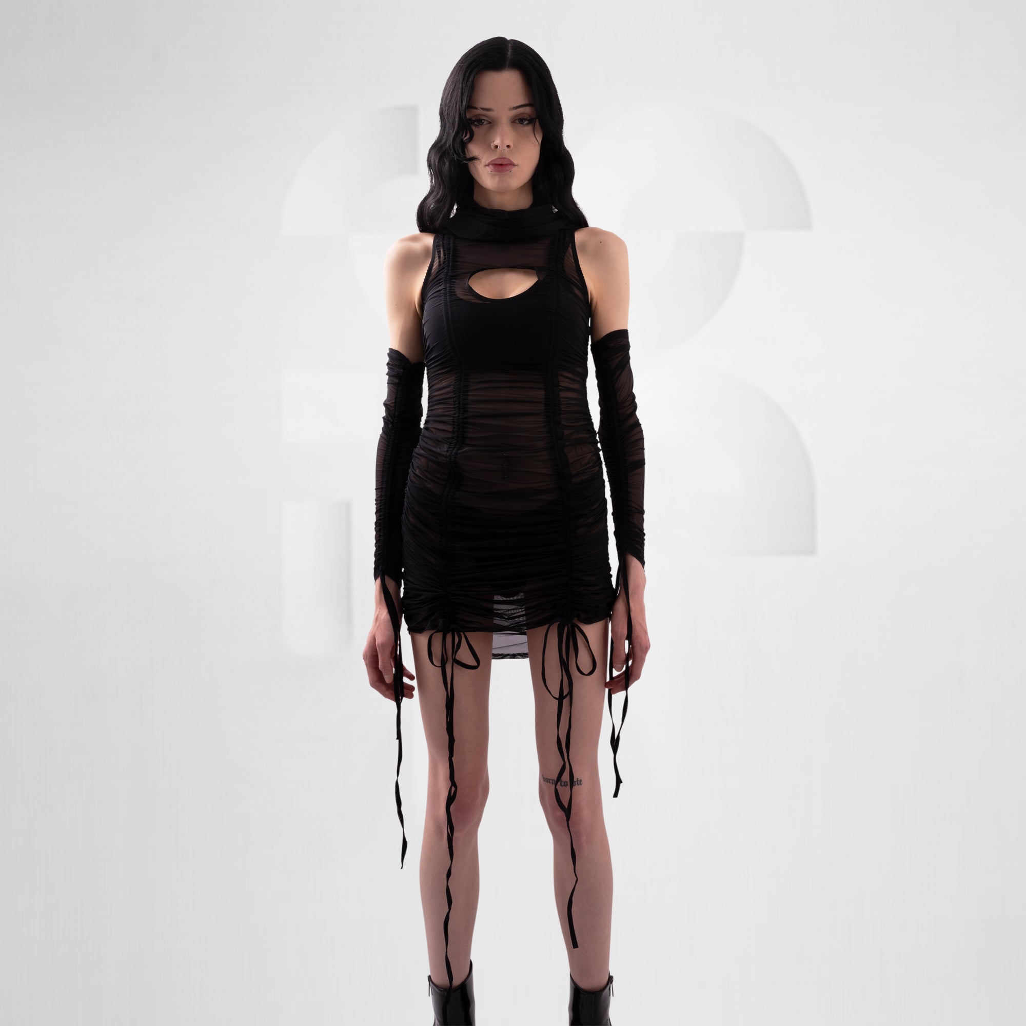 Model wearing a black outfit with cut-out design on a white background