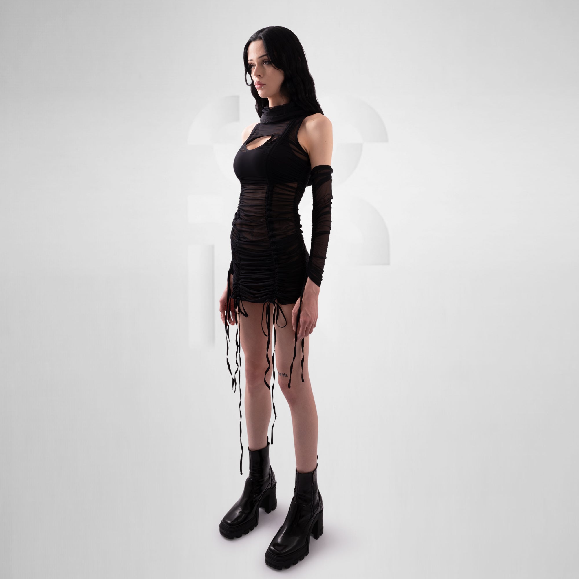 Person wearing a black outfit with long gloves and boots on a white background