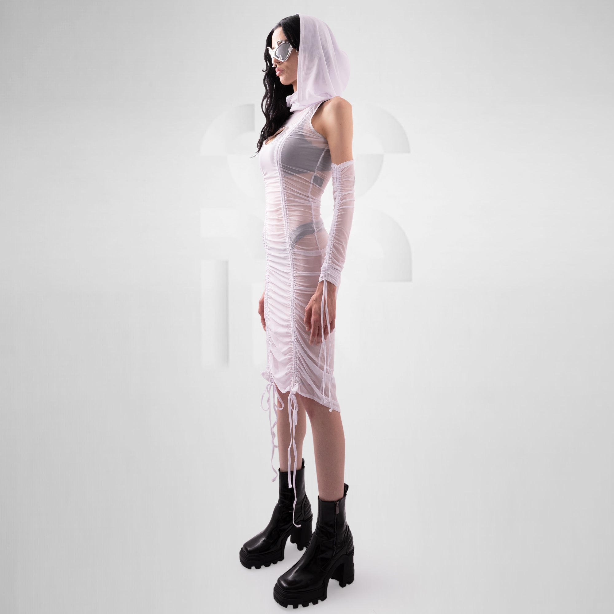 Person wearing a sheer white dress with black boots on a white background
