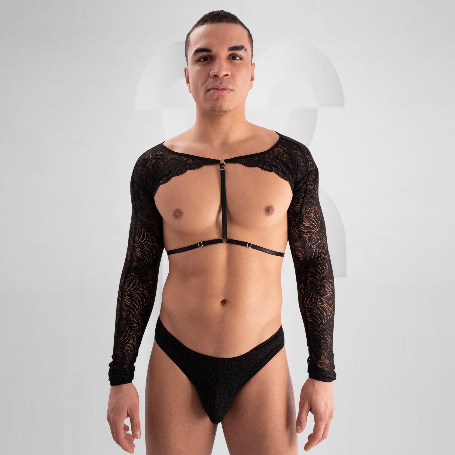 The outfit in the image consists of a bold, fashion-forward design. It features a black lace top with long sleeves and intricate patterns. The top is open at the chest with a strap across the front. The bottom is a matching black lace piece. This ensemble presents a unique and striking look, likely designed for an expressive or avant-garde fashion setting.