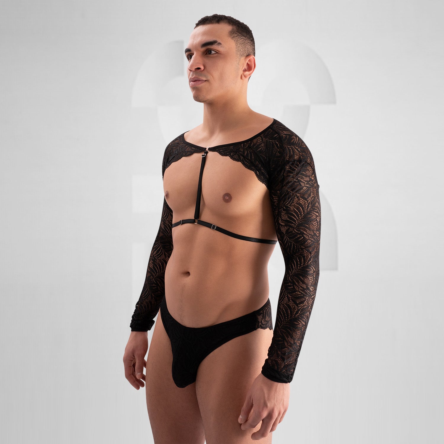 The outfit in the image consists of a bold, fashion-forward design. It features a black lace top with long sleeves and intricate patterns. The top is open at the chest with a strap across the front. The bottom is a matching black lace piece. This ensemble presents a unique and striking look, likely designed for an expressive or avant-garde fashion setting.