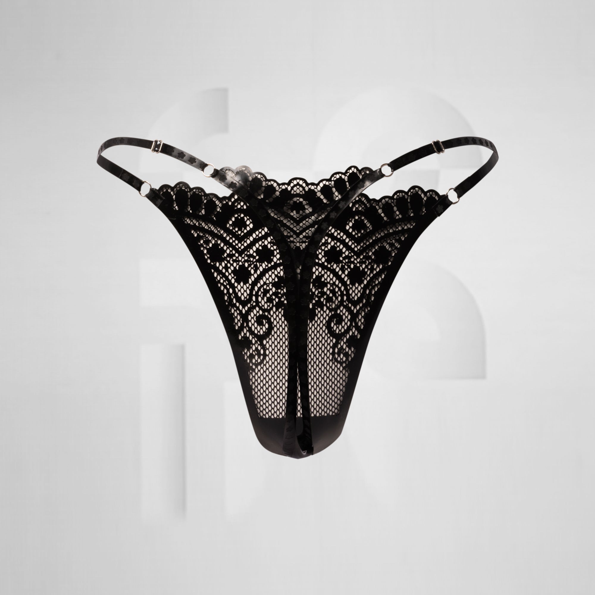 black latex thong in front of grey background