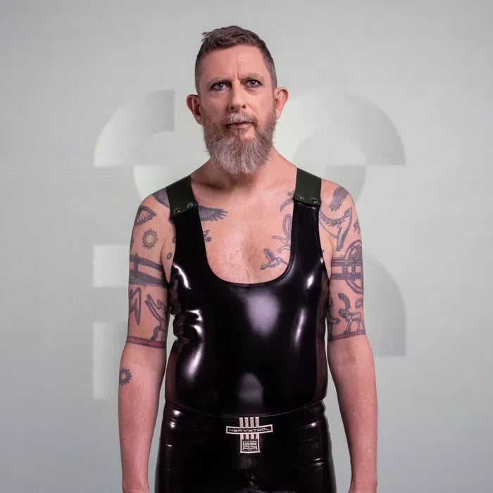 The image features a bold Latex Tank Top with Removable Straps, showcasing a striking glossy finish that complements the wearer's physique. The design features a deep scoop neck and sleek lines, enhanced by the detachable straps that offer versatility in styling. Perfect for clubbing or embracing the kink scene, this tank top makes a daring statement while ensuring maximum comfort and confidence.
