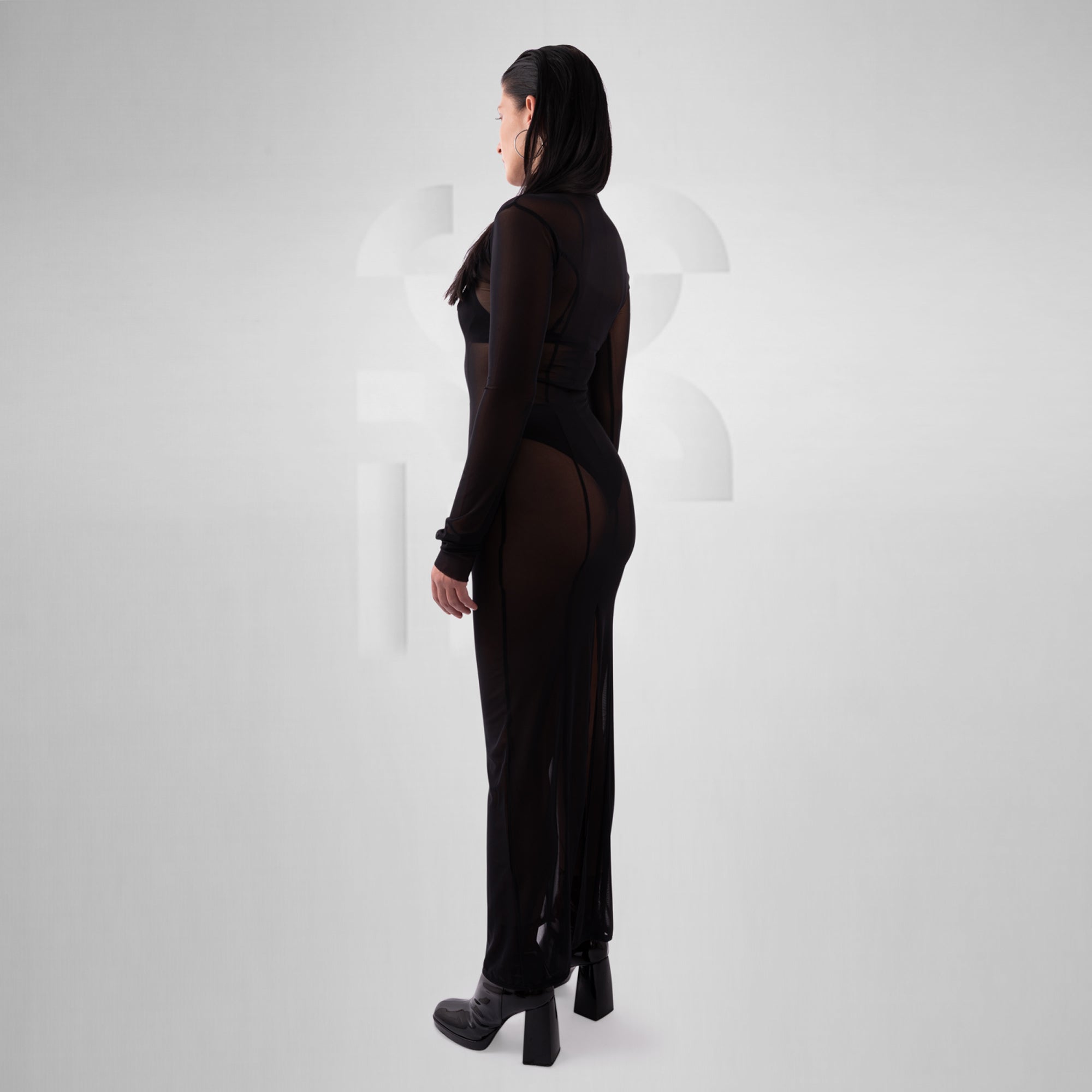 Person wearing a black outfit with sheer panels on a white background