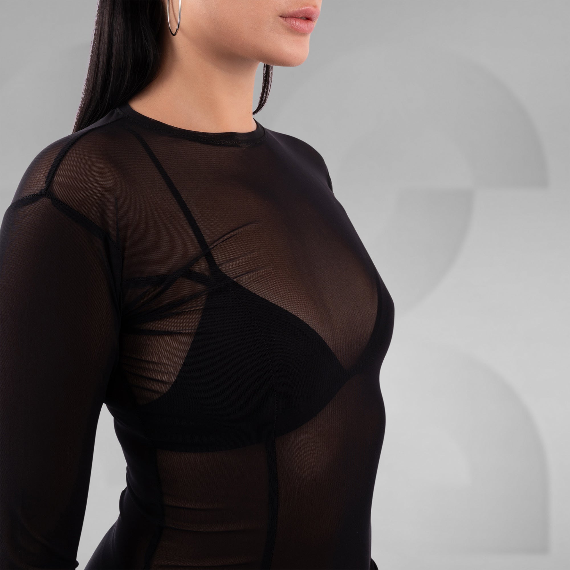 Black sheer long-sleeve top worn by a person on a gray background