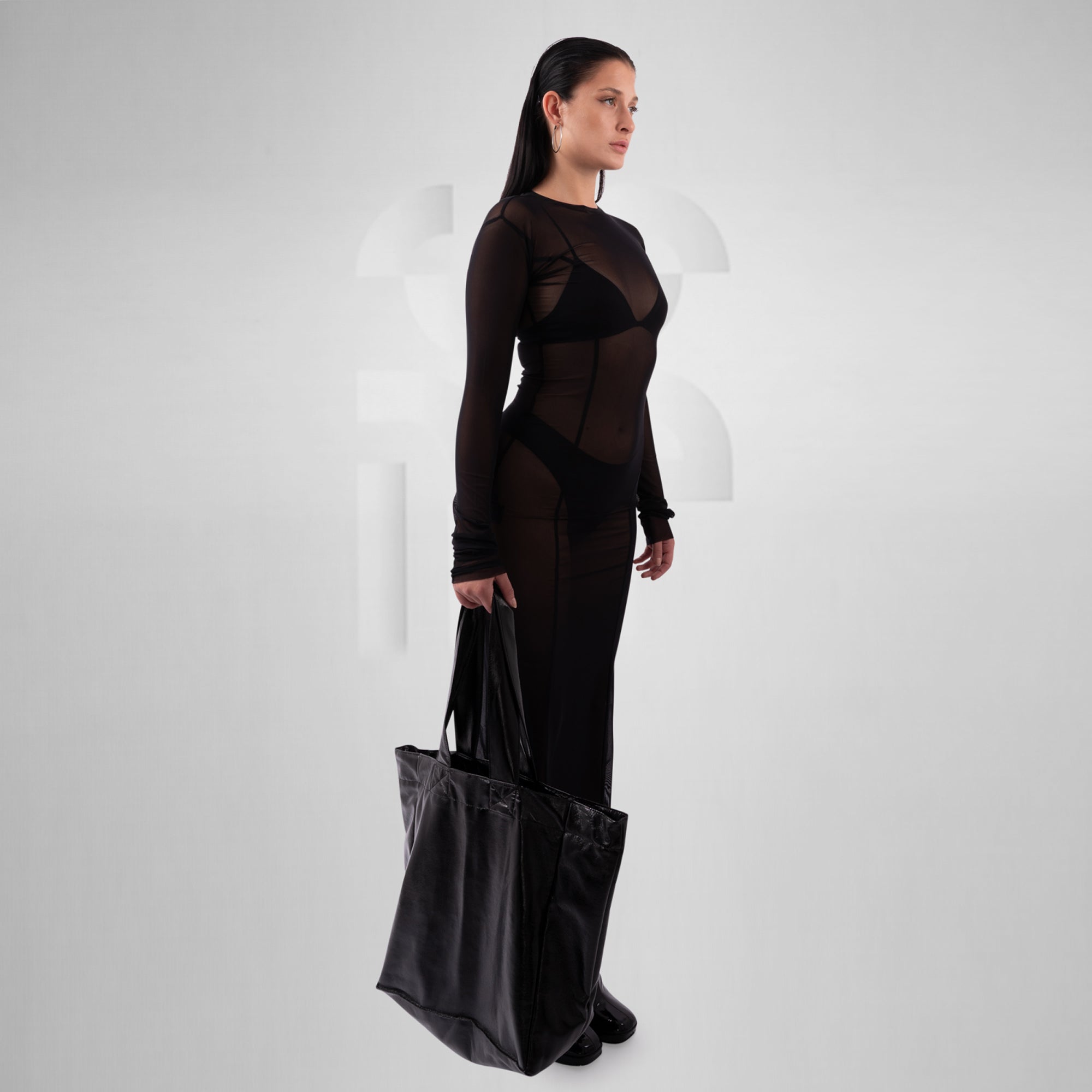 Woman holding a black tote bag against a white background