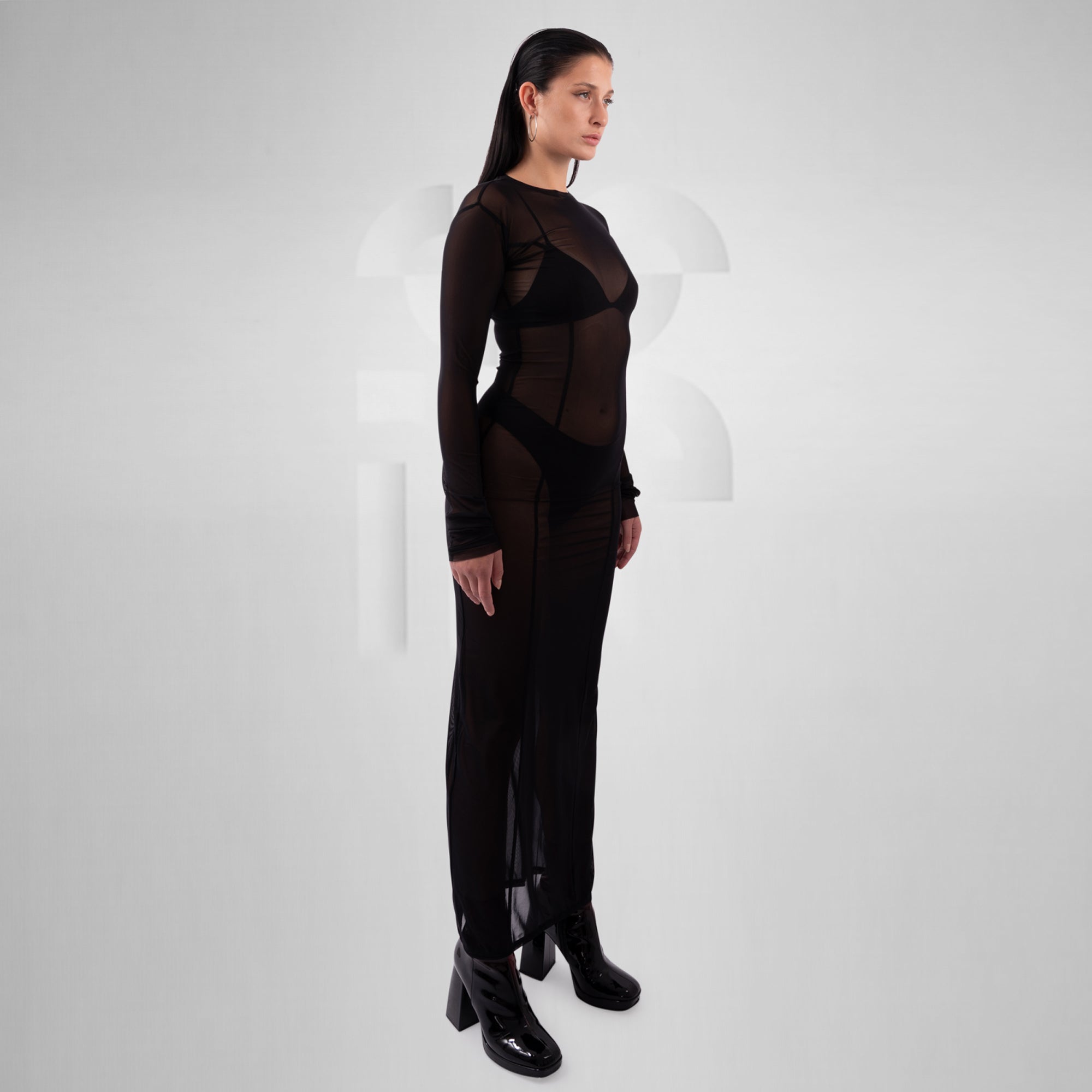 Woman wearing a black outfit with sheer panels on a white background