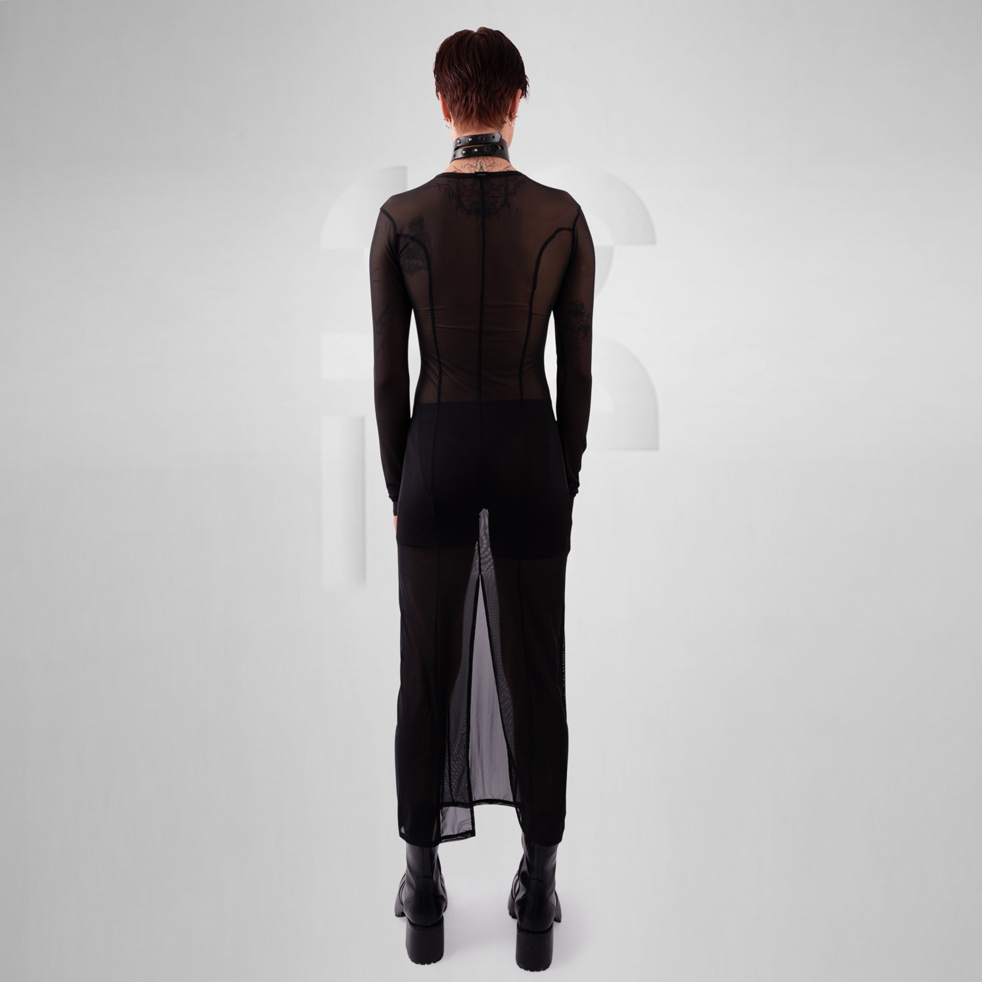 Person wearing a black outfit with sheer panels on a white background