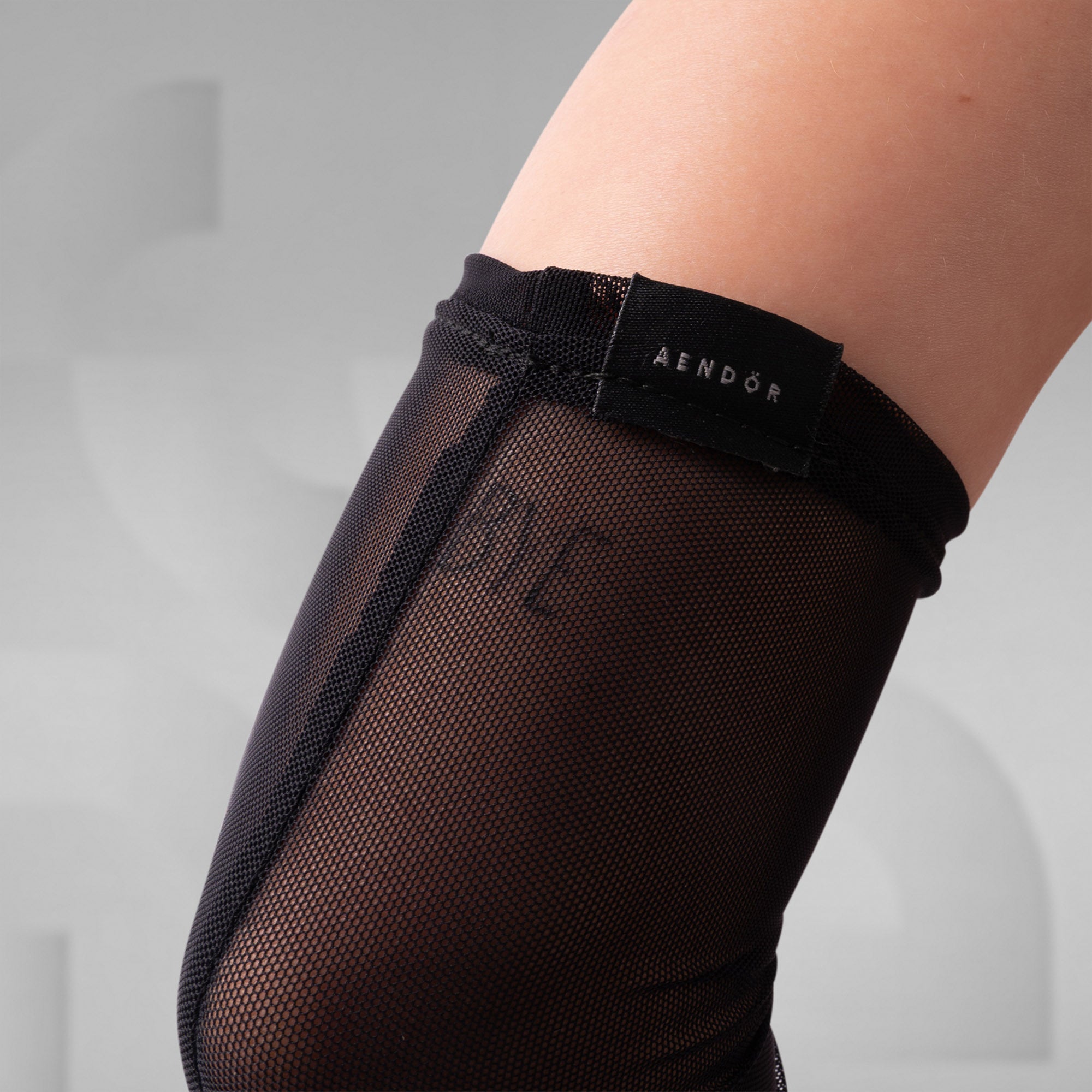 Black sheer stockings with mesh design and 'Aendor' branding on a neutral background