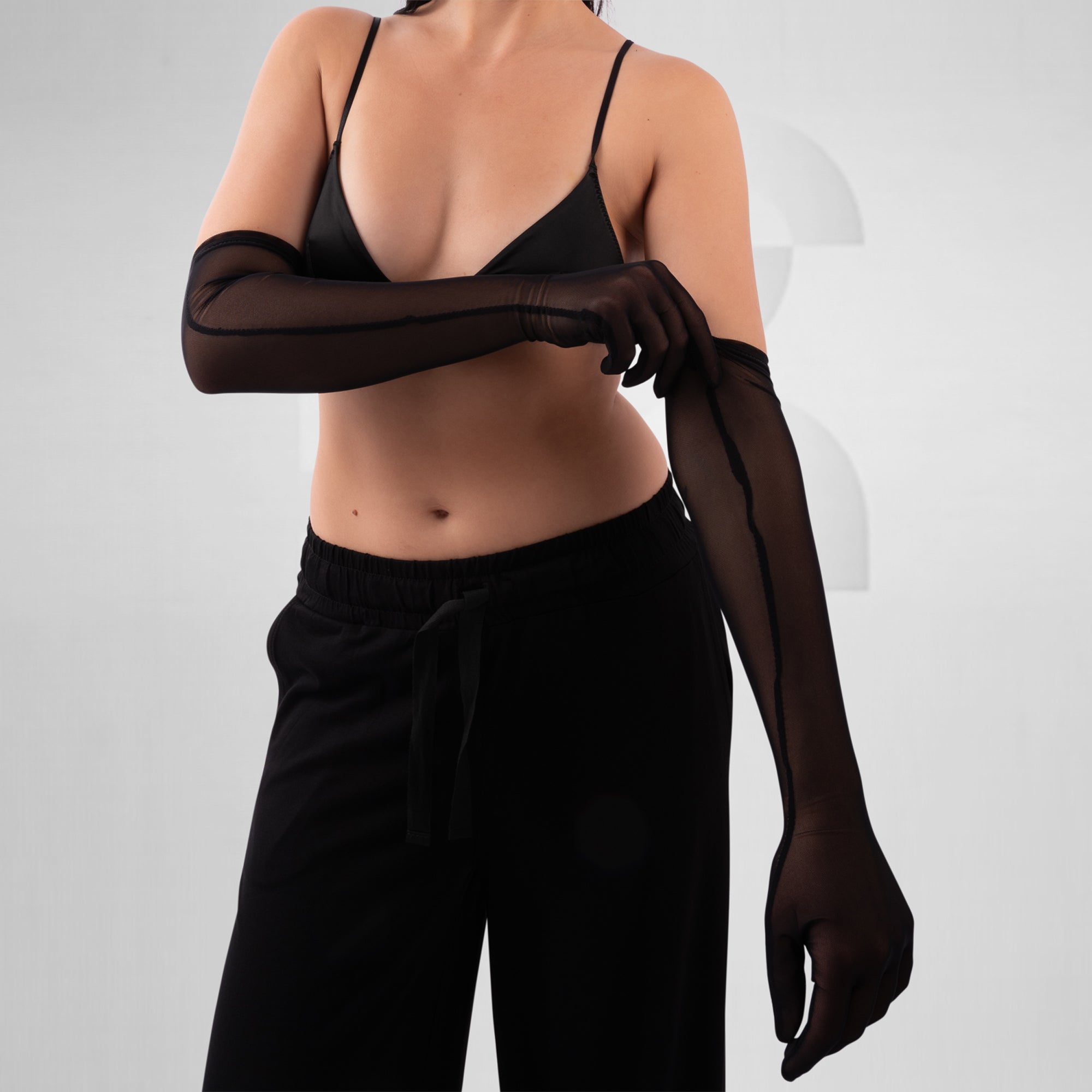 Person wearing a black bra and black gloves on a plain background