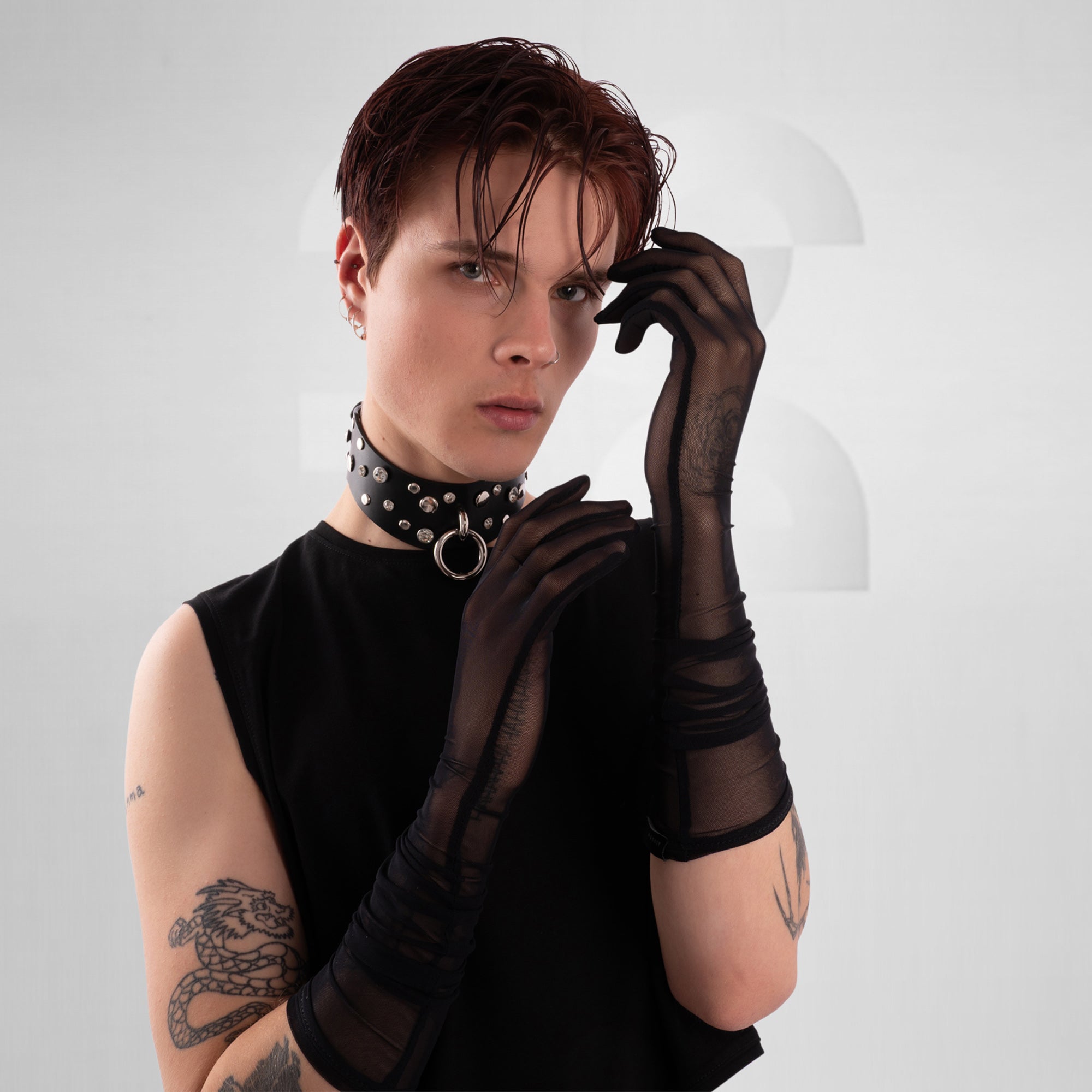 Person wearing black gloves and a choker with a white background