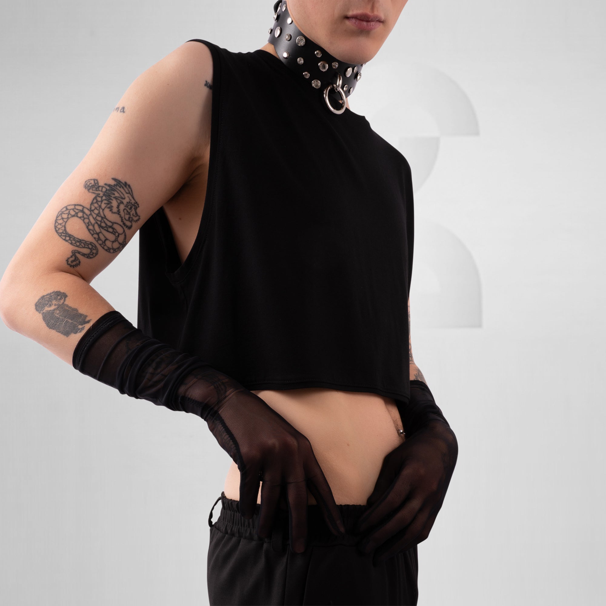 Person wearing a black sleeveless top with sheer sleeves on a plain background