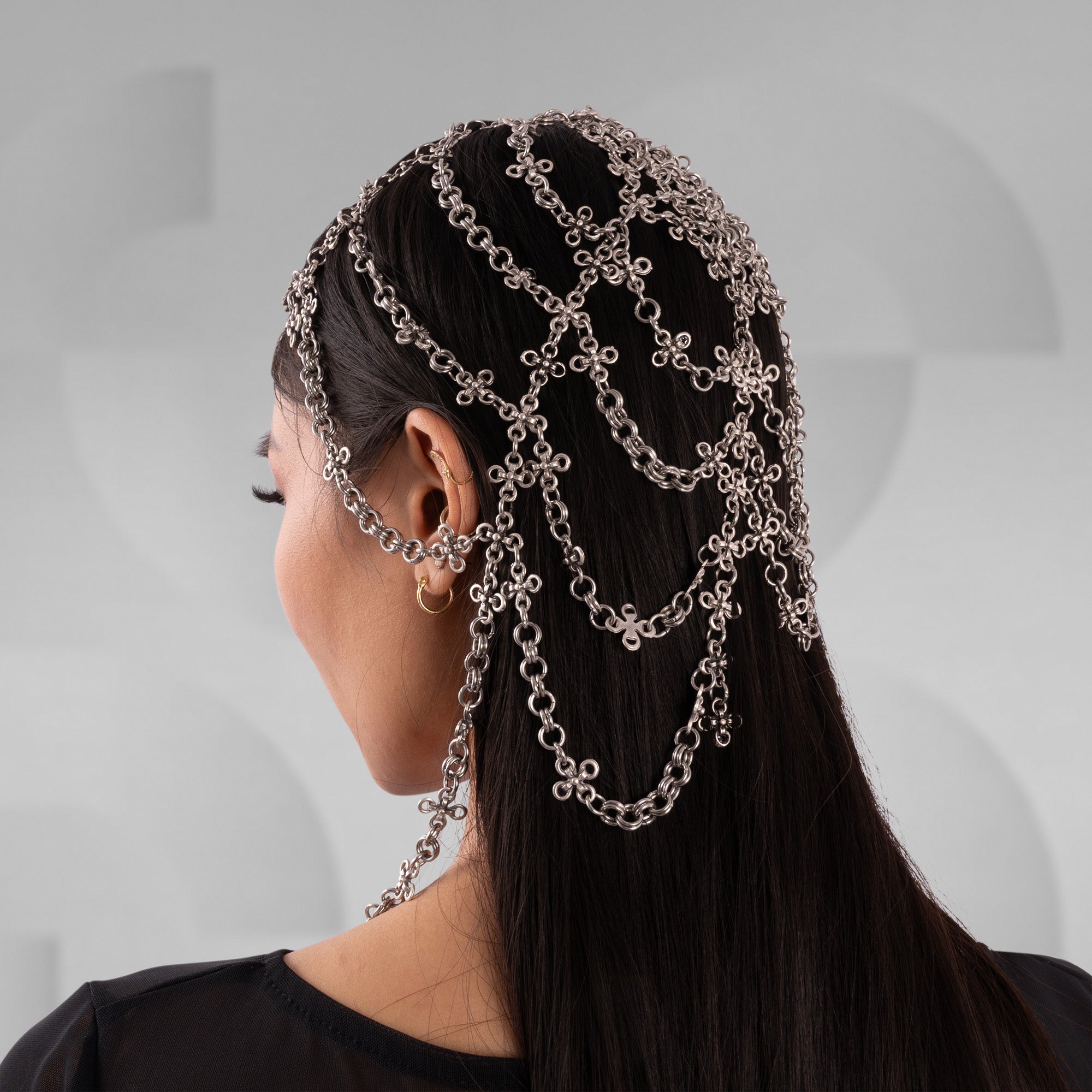 Person with chains in their hair against a neutral background