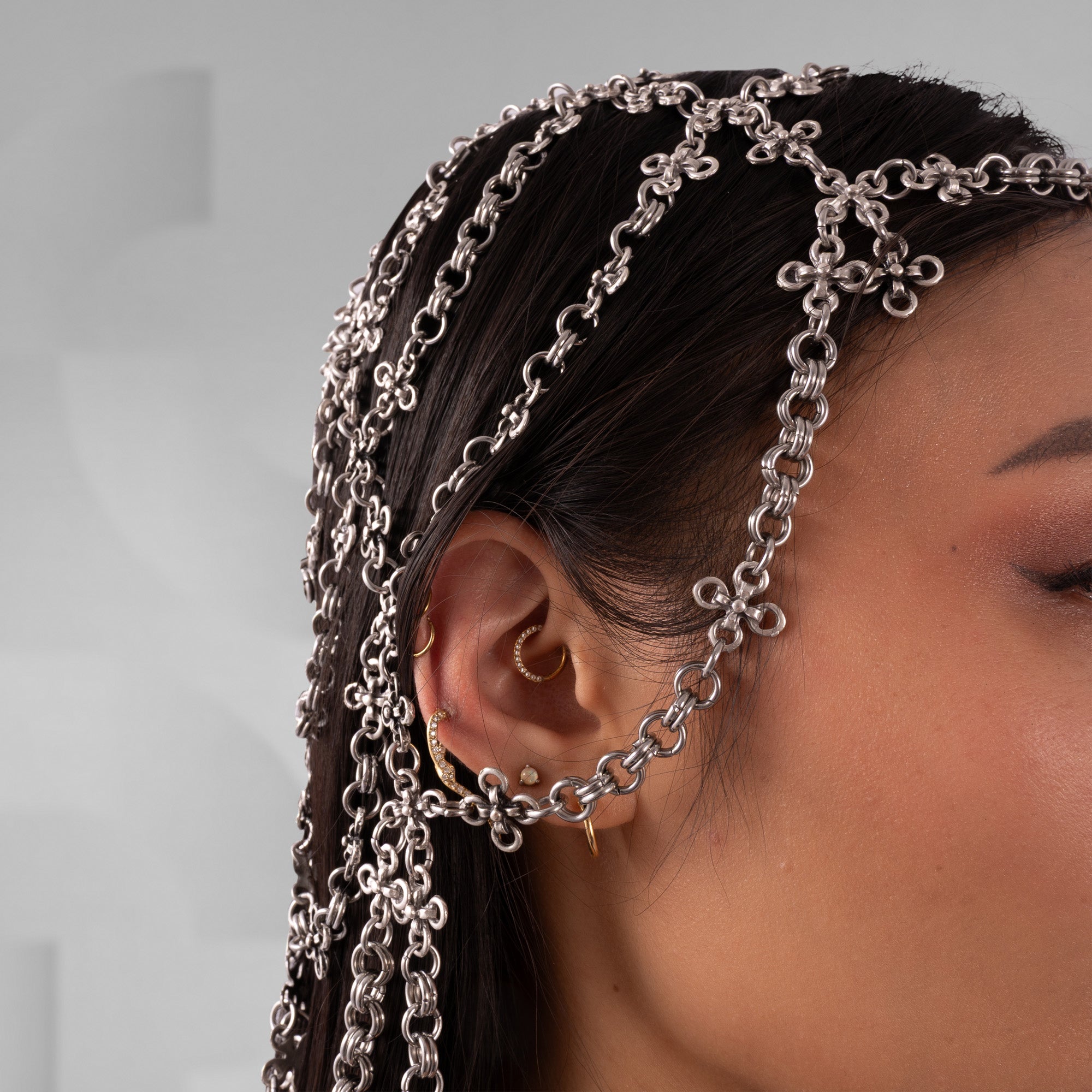 Person wearing a silver chain headband with a neutral background