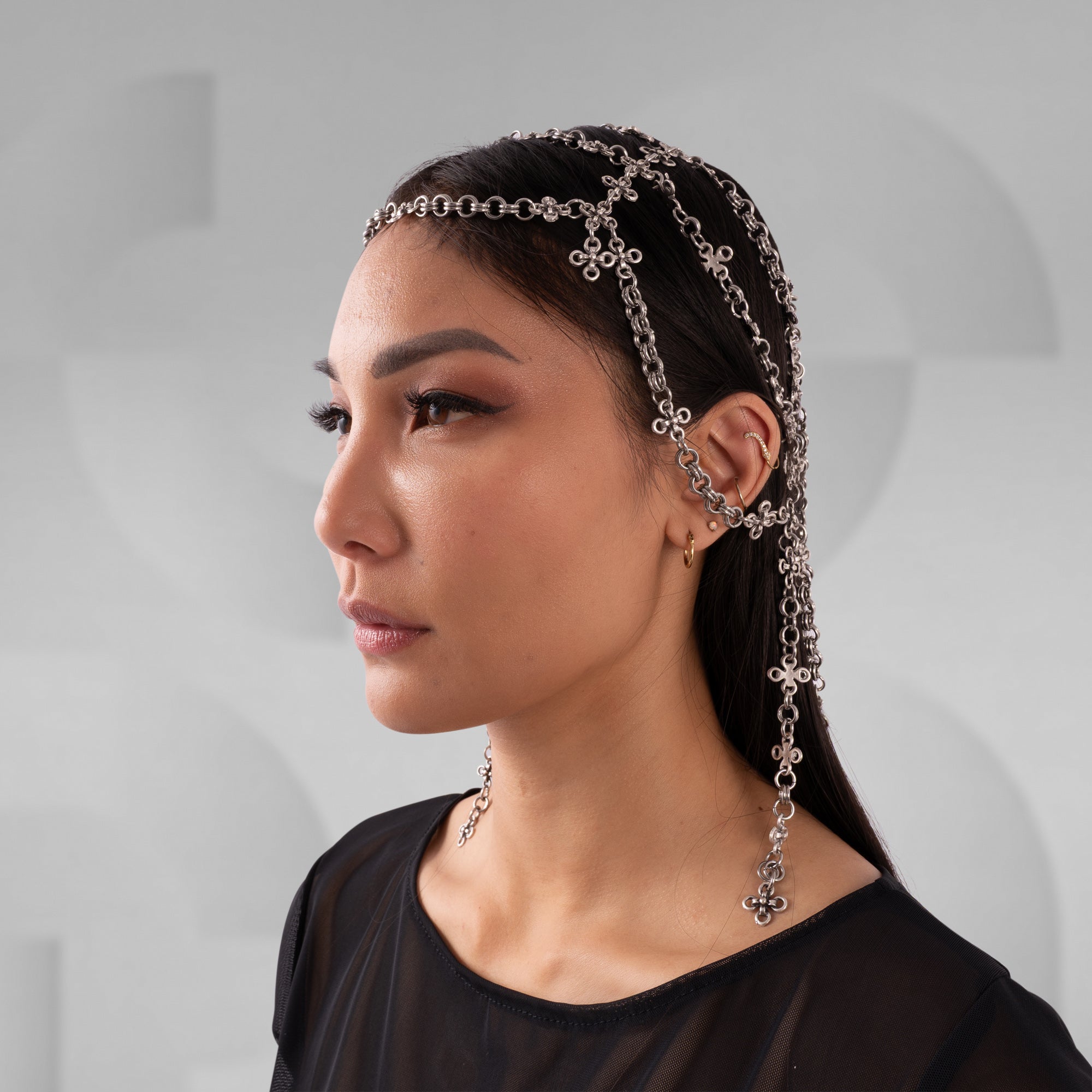 Woman wearing a chain headband with a neutral background
