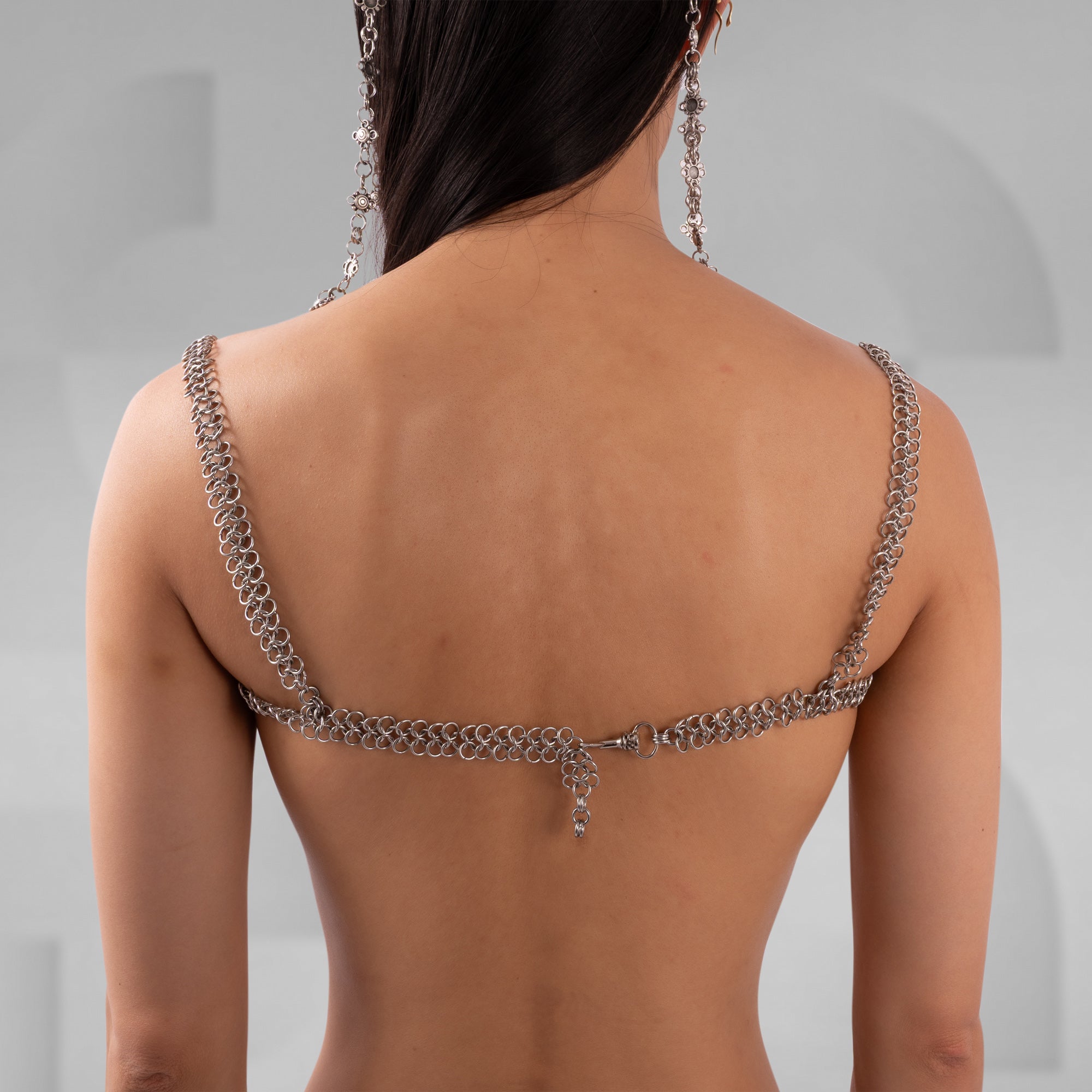 Person wearing a chain backless top against a neutral background
