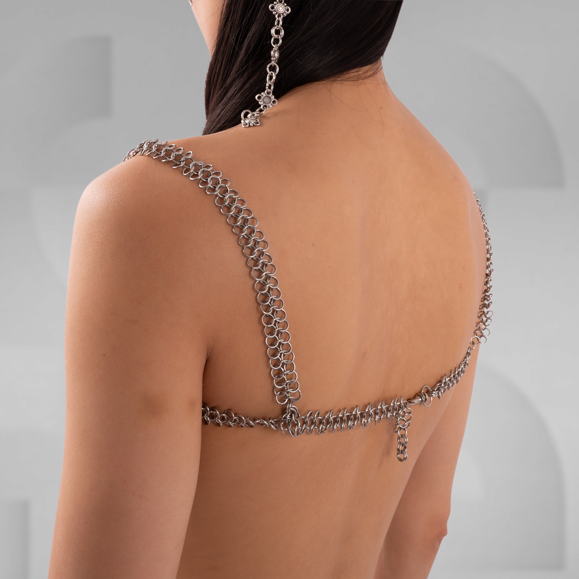 Person wearing a chain backless top against a neutral background