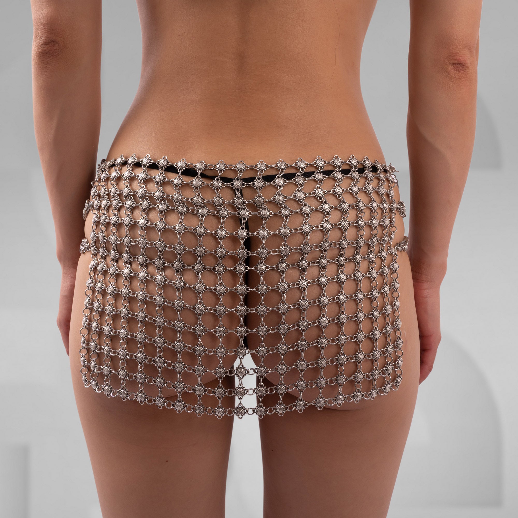 Person wearing a sparkling chainmail skirt on a plain background