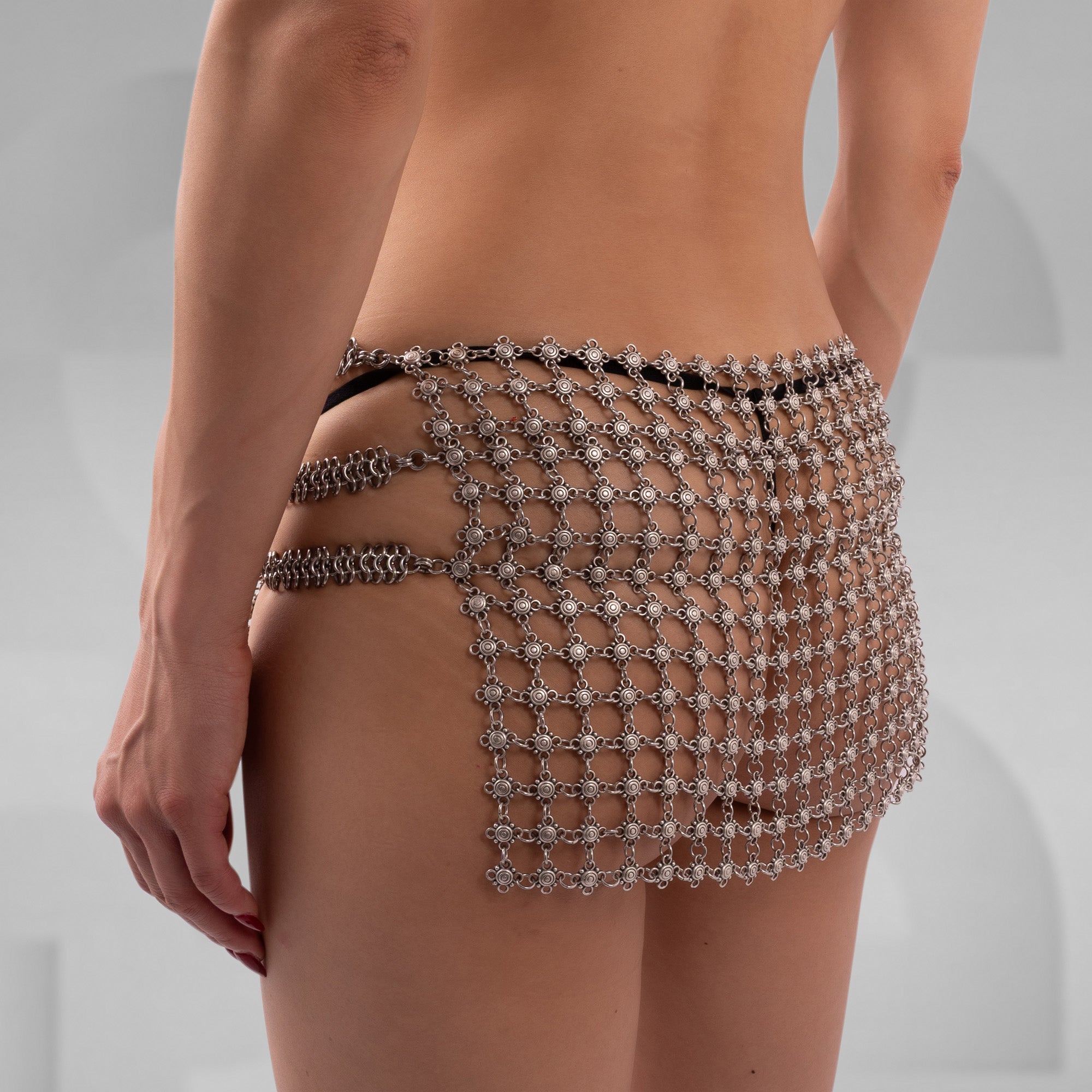 Person wearing a chainmail skirt on a plain background