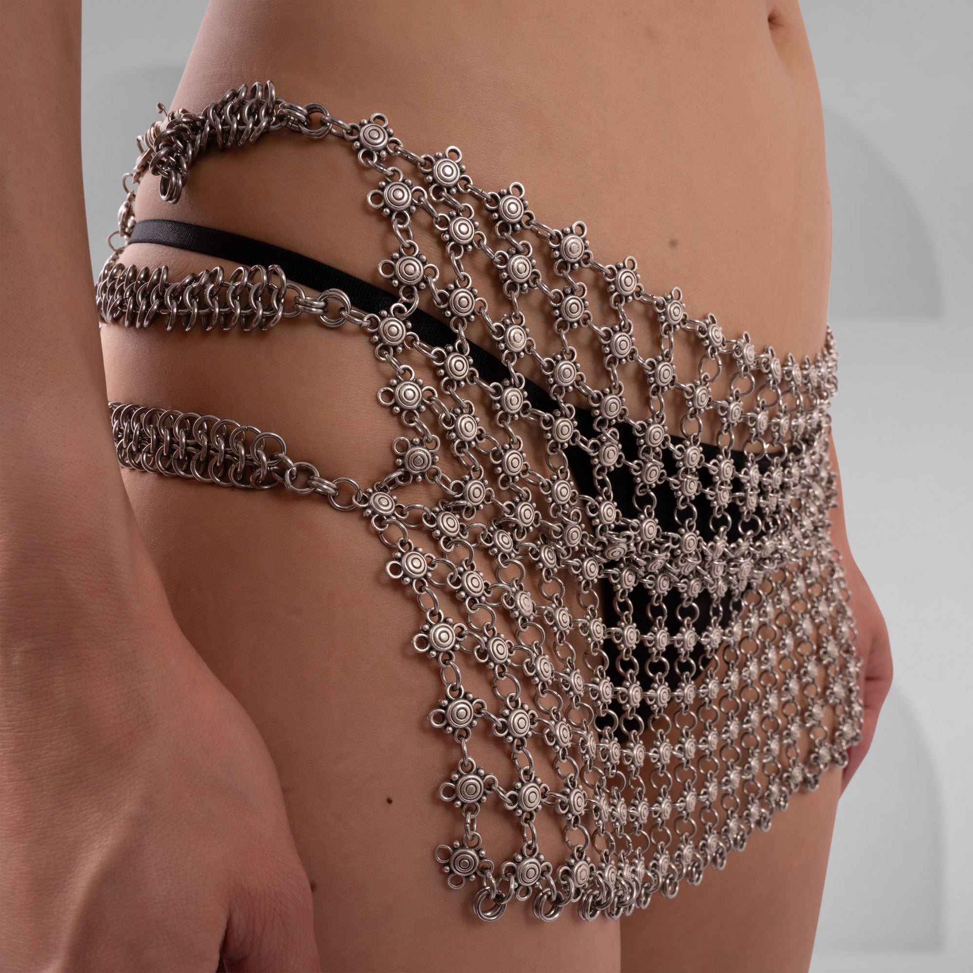 Metallic chain body harness on a person against a neutral background