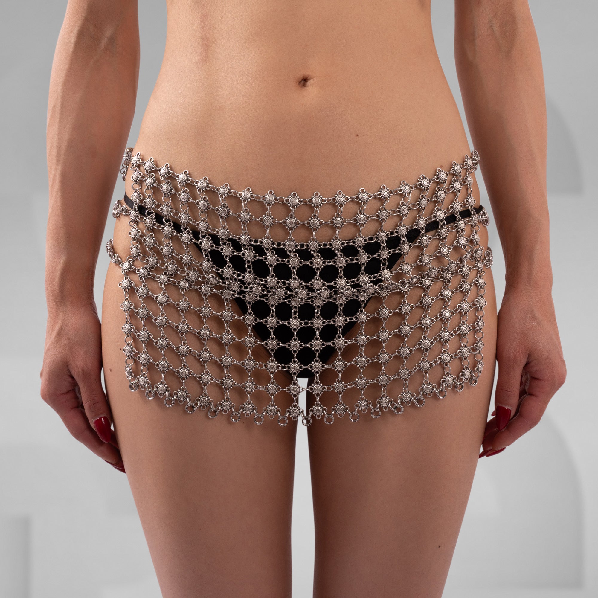 Person wearing a decorative waist chain on a plain background