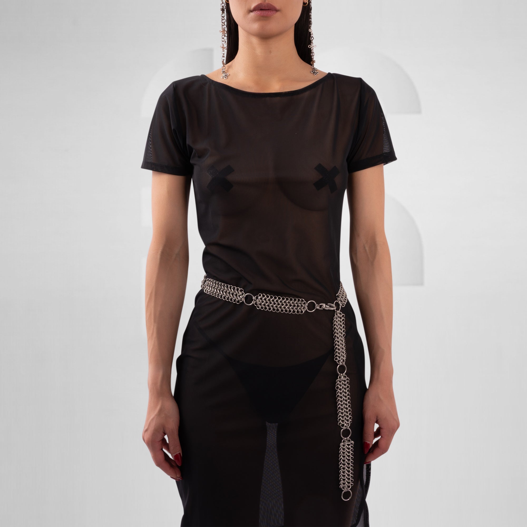 Person wearing a black outfit with a chain belt on a white background