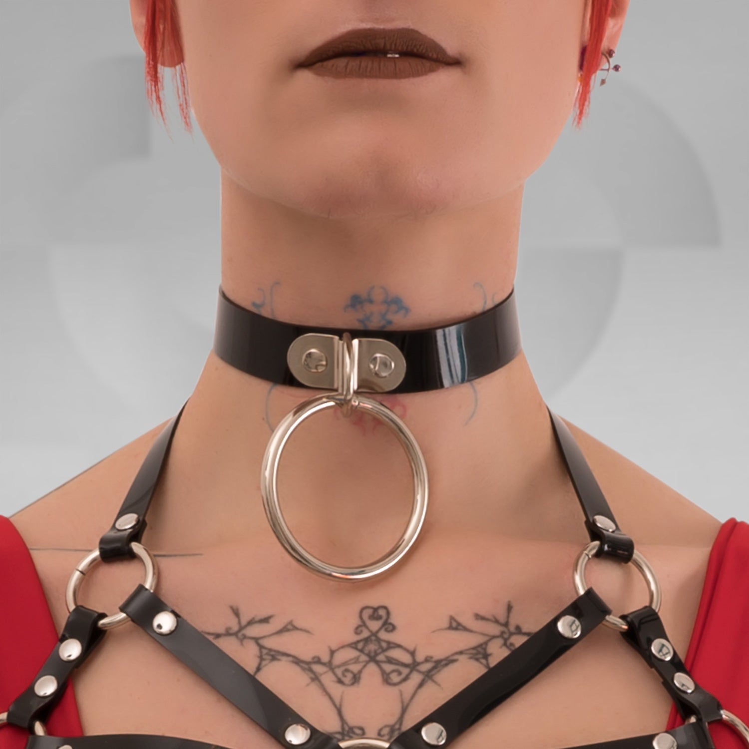 A close-up of the Minimalist Black PVC Choker from Miss Overdose, showcasing its bold oversized ring in gold. The choker, crafted from sleek leather, embodies a blend of elegance and playful kink, perfect for clubwear, adding a striking touch to any outfit.