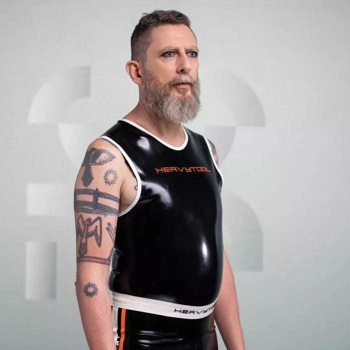 The image features a striking outfit from HeavyTool Gear, showcasing a sleek black sleeveless top with matching shorts. Crafted from glossy latex, this ensemble hugs the body for a flattering fit, complete with a bold logo on the waistband. Perfect for the party scene, it combines edgy style with comfort, making it an ideal choice for anyone looking to make a statement while embracing their individuality.