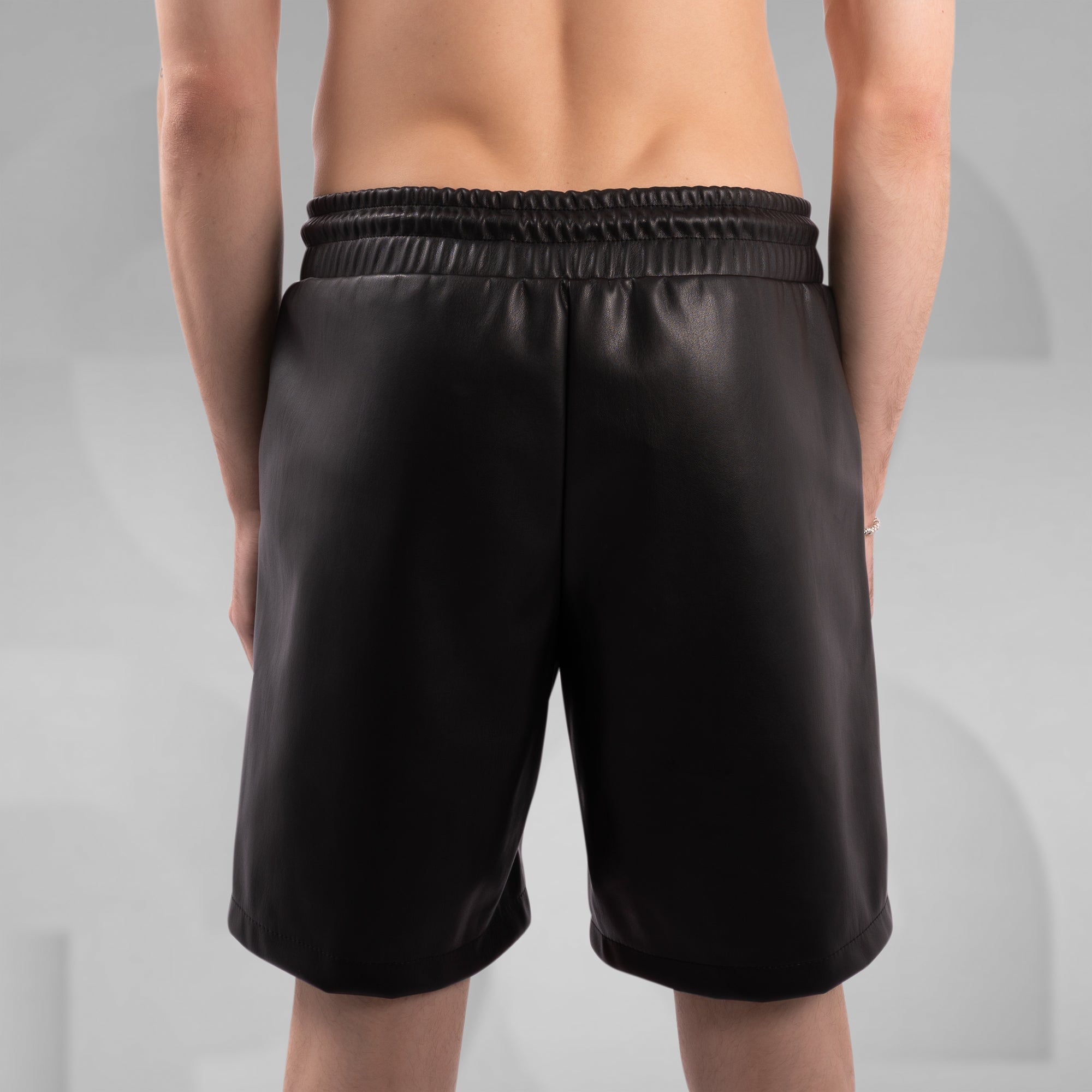 Black shorts worn by a person on a gray background