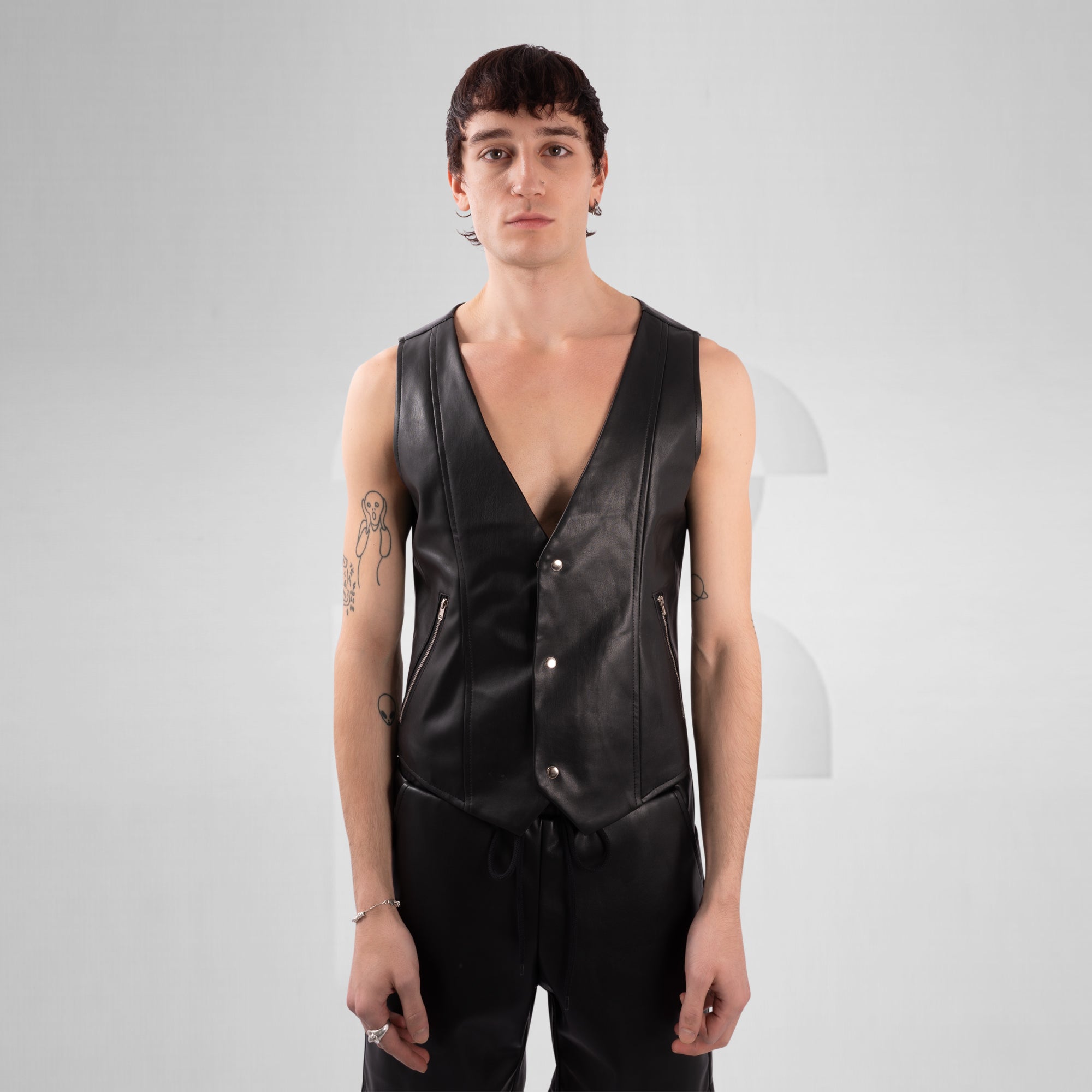 Person wearing a black leather vest on a gray background