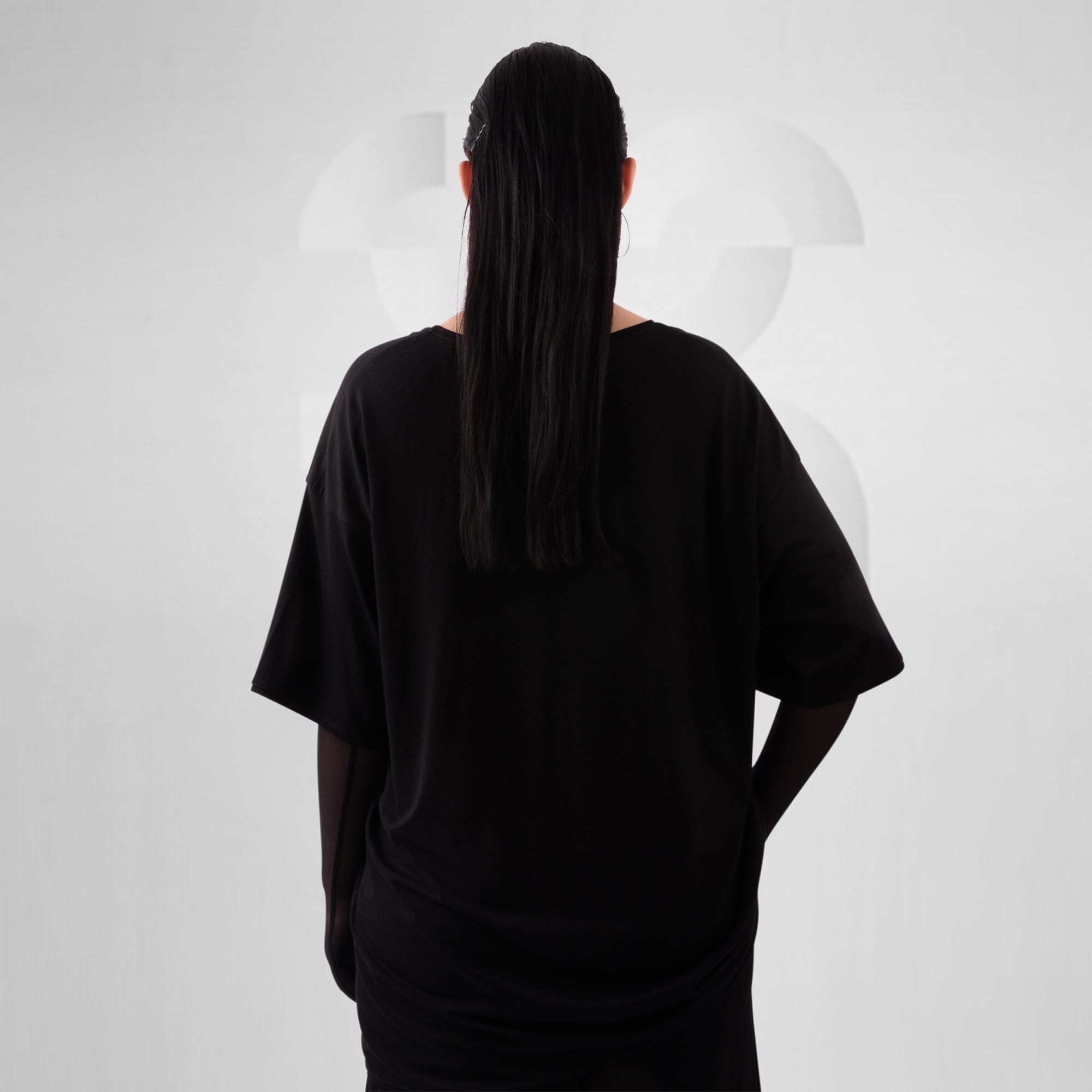 Person wearing a loose-fitting black t-shirt against a white background