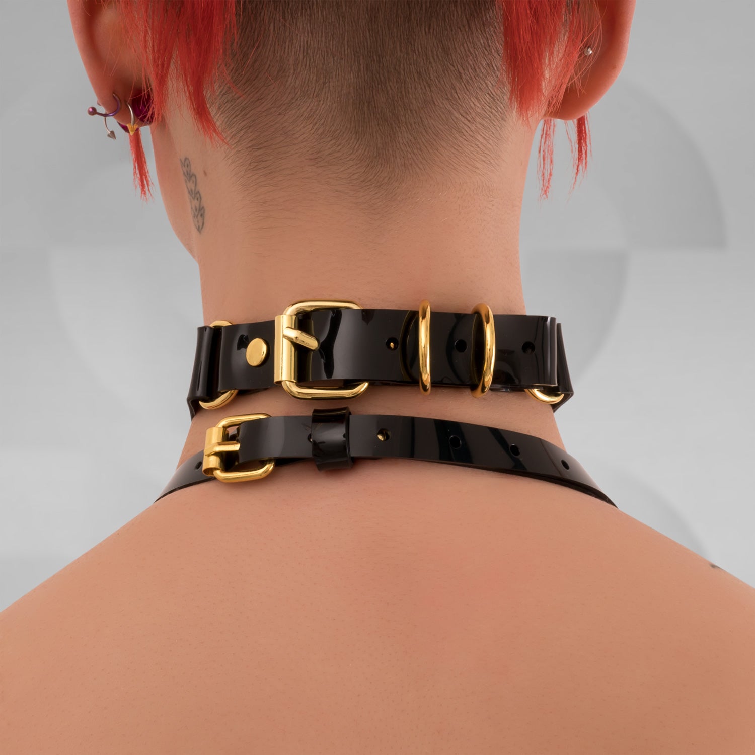A black PVC Double Ring Choker showcasing elegant silver or gold rings, positioned against a simple backdrop.