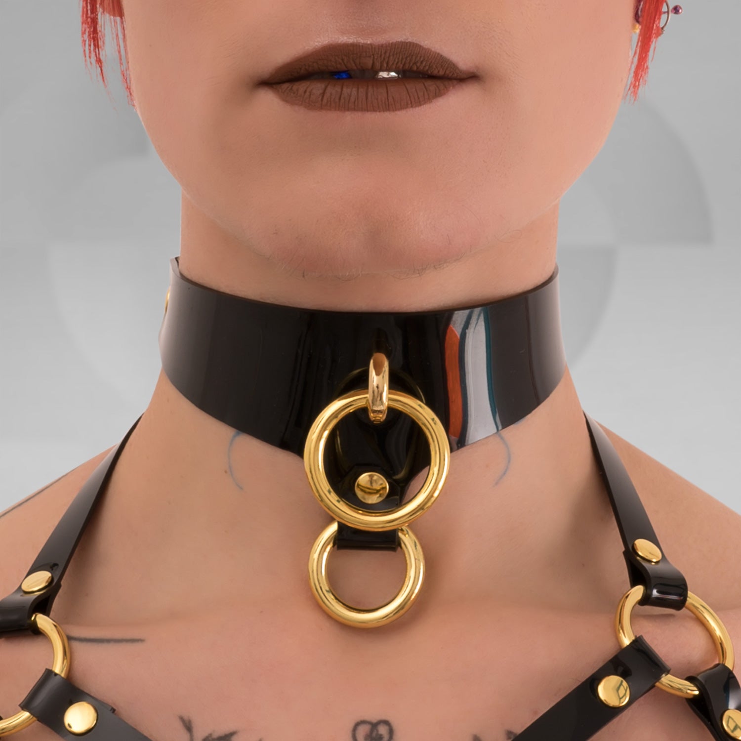 A black PVC Double Ring Choker showcasing elegant silver or gold rings, positioned against a simple backdrop..