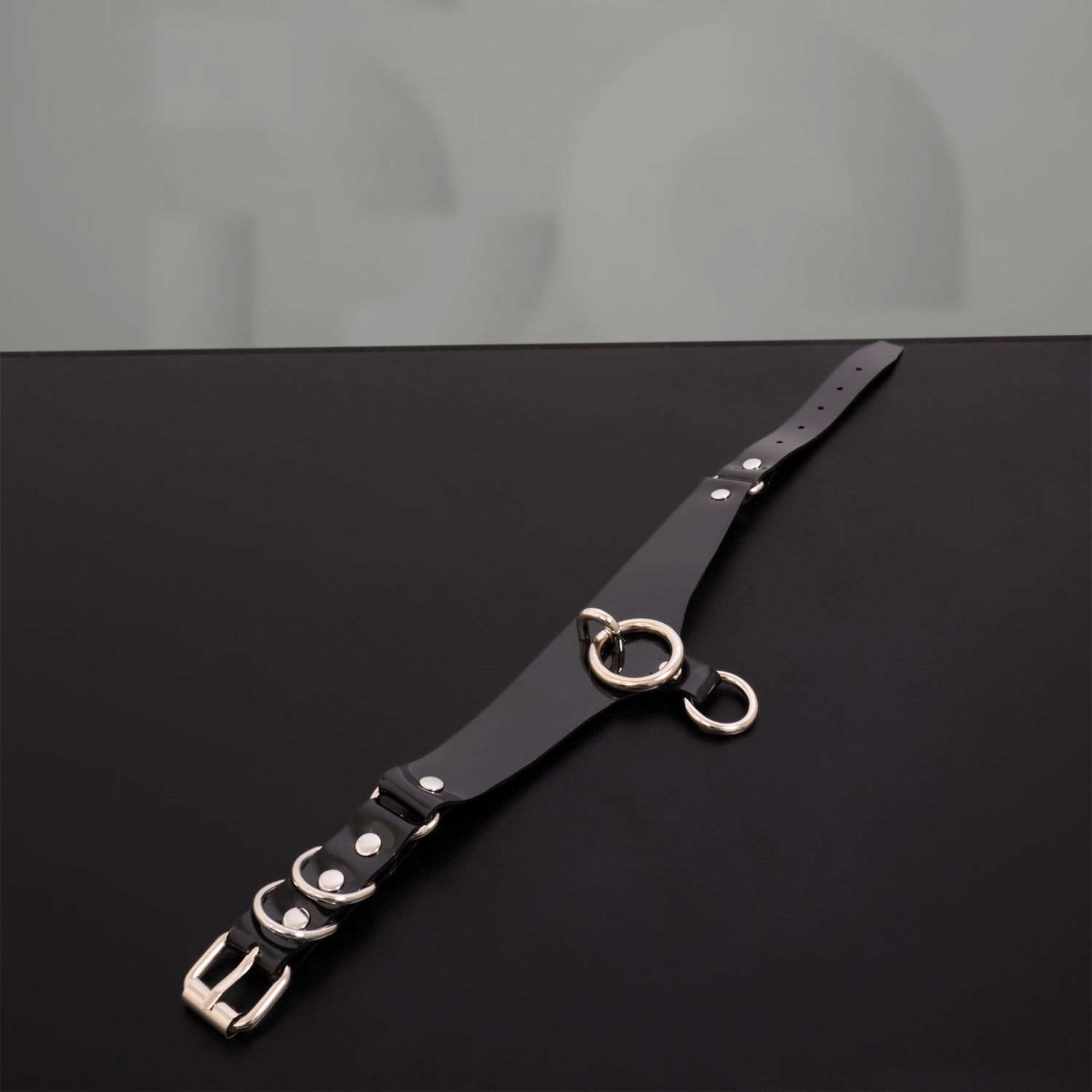 A black PVC Double Ring Choker showcasing elegant silver or gold rings, positioned against a simple backdrop.