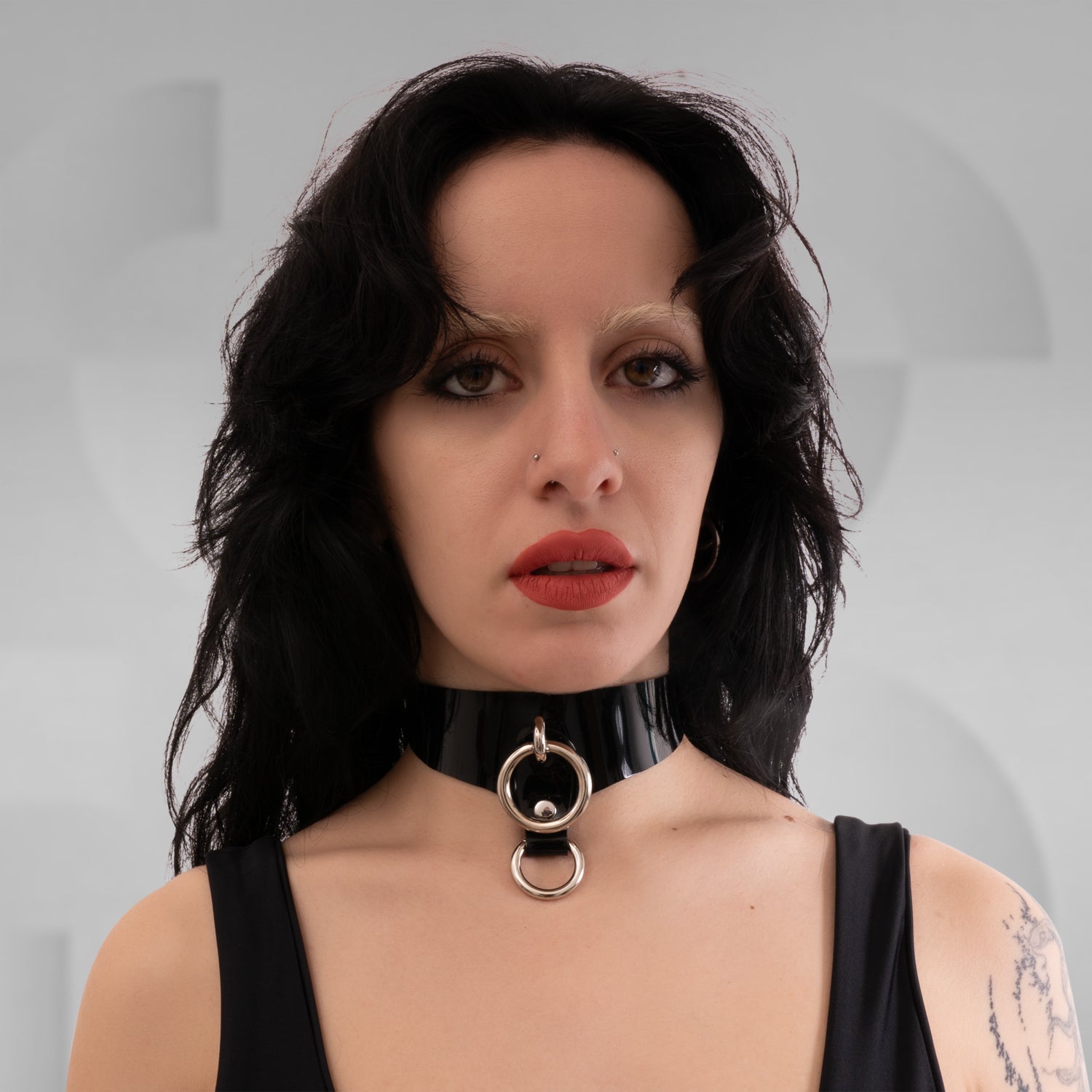 A black PVC Double Ring Choker showcasing elegant silver or gold rings, positioned against a simple backdrop.
