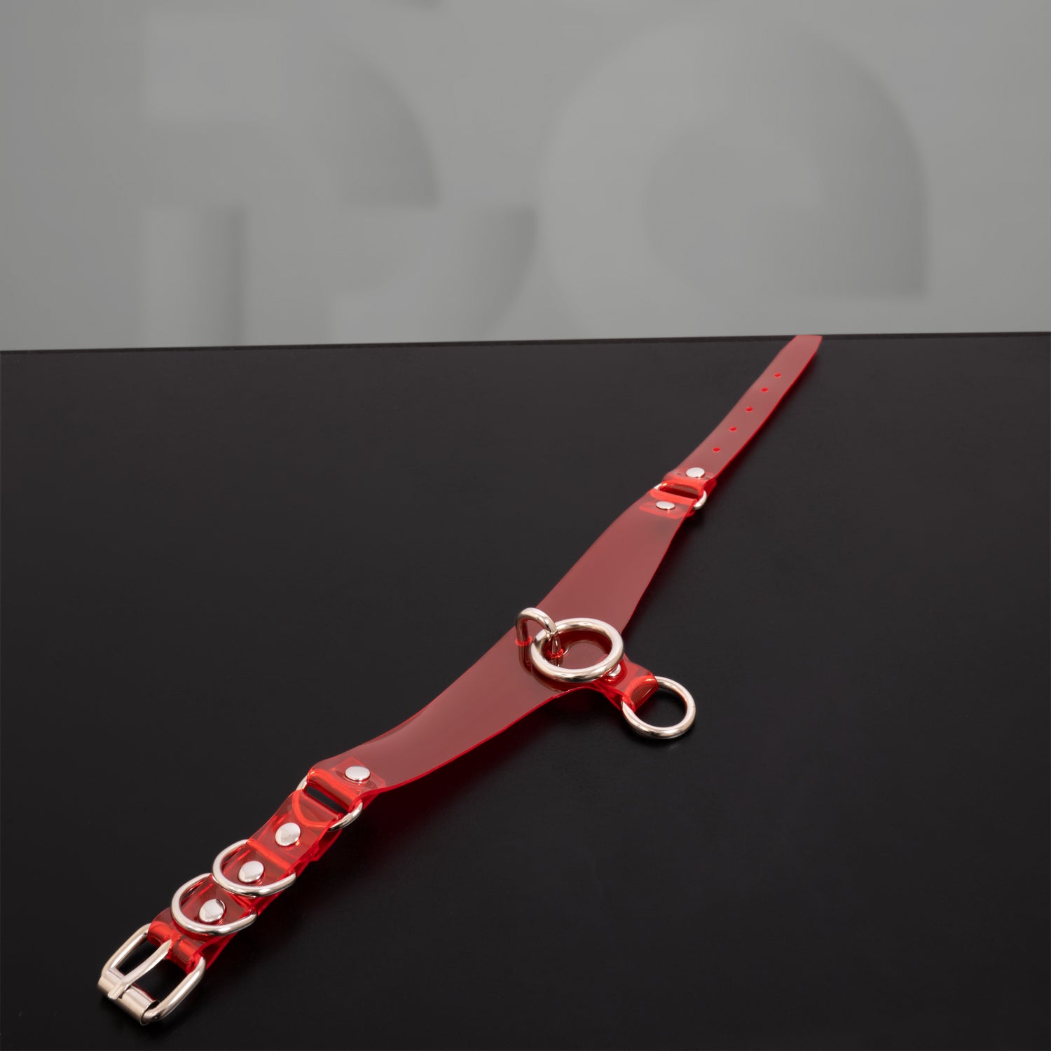 This image features a model wearing a striking red PVC choker that beautifully accentuates her neckline. The choker showcases a high-gloss finish and includes bold metallic rings, adding an edgy yet elegant touch to her look. With its vibrant color and sleek design, this accessory embodies confidence and style, making it perfect for both everyday wear and special occasions