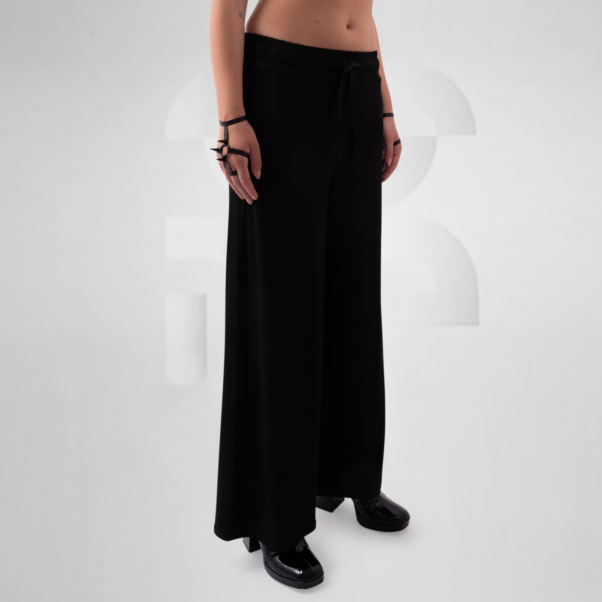 Person wearing black wide-leg pants on a white background