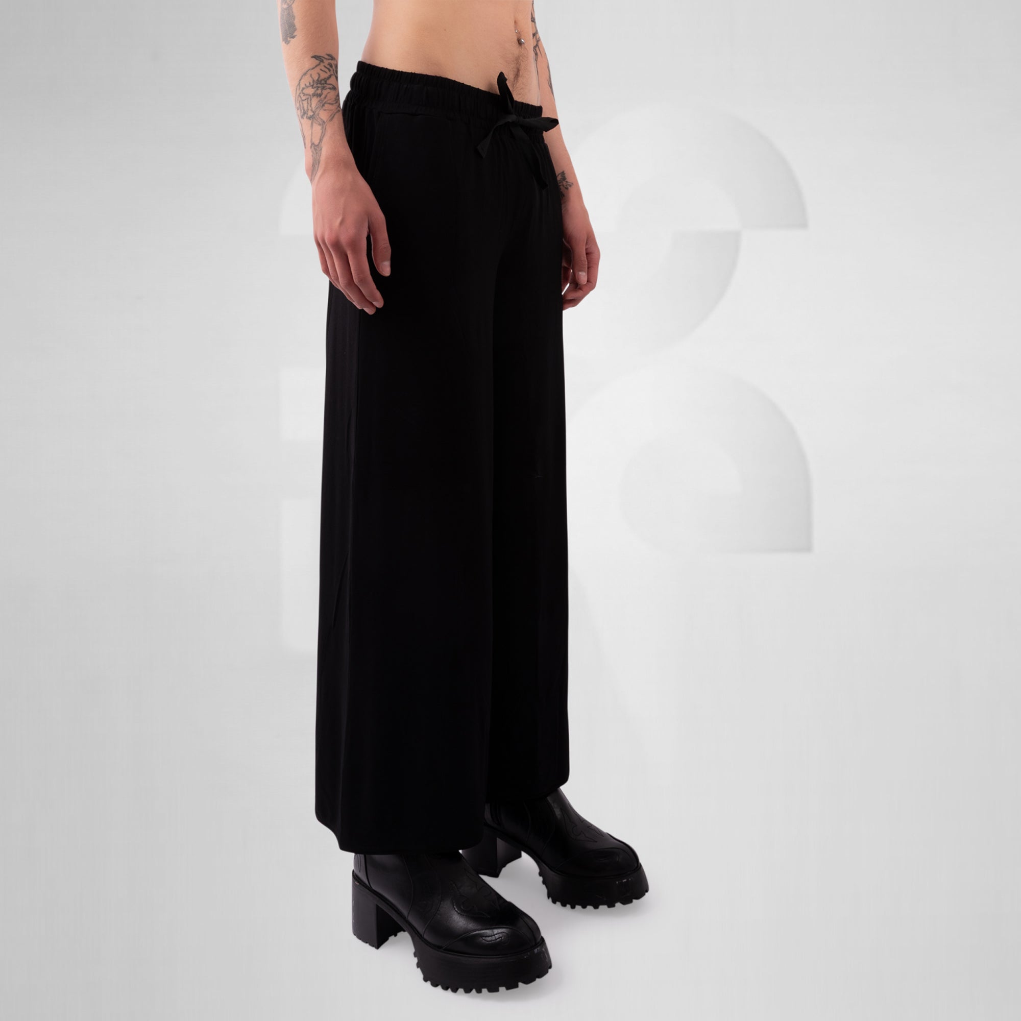 Person wearing black wide-leg pants and black shoes on a white background