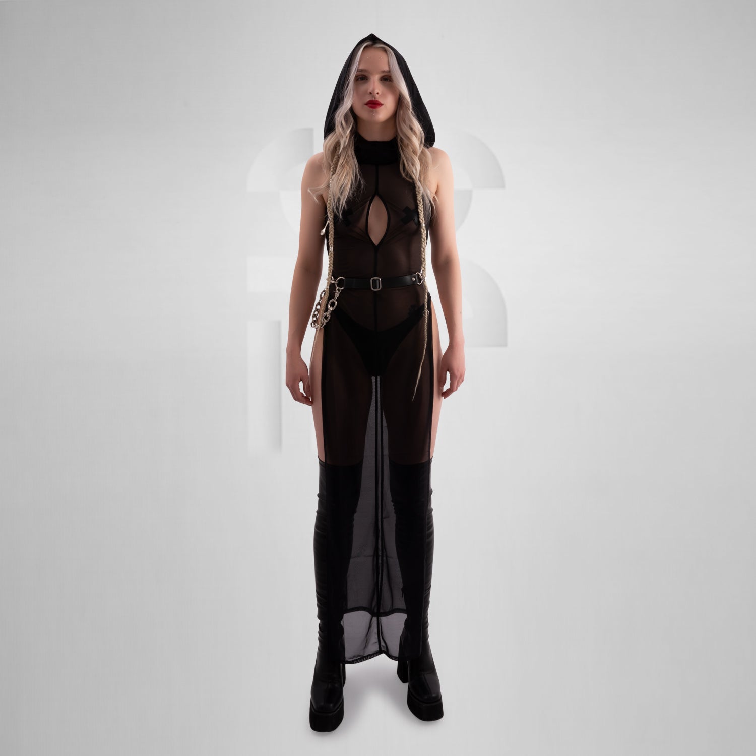 Close-up of a person wearing a bold, high-slit black sheer dress paired with a statement black belt featuring a chunky silver chain draped across the hip, showcasing an edgy and provocative fashion accessory perfect for nightlife or avant-garde styling.