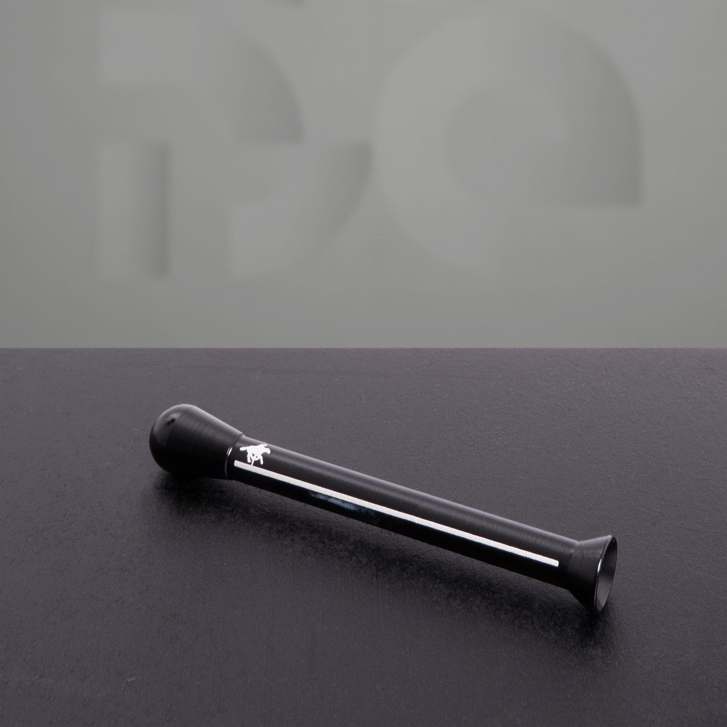 Sleek black straw with a flared tip and aerodynamic design, featuring a white horse logo. Resting on a dark textured surface, this elegant and reusable straw combines style with functionality for a premium drinking experience.