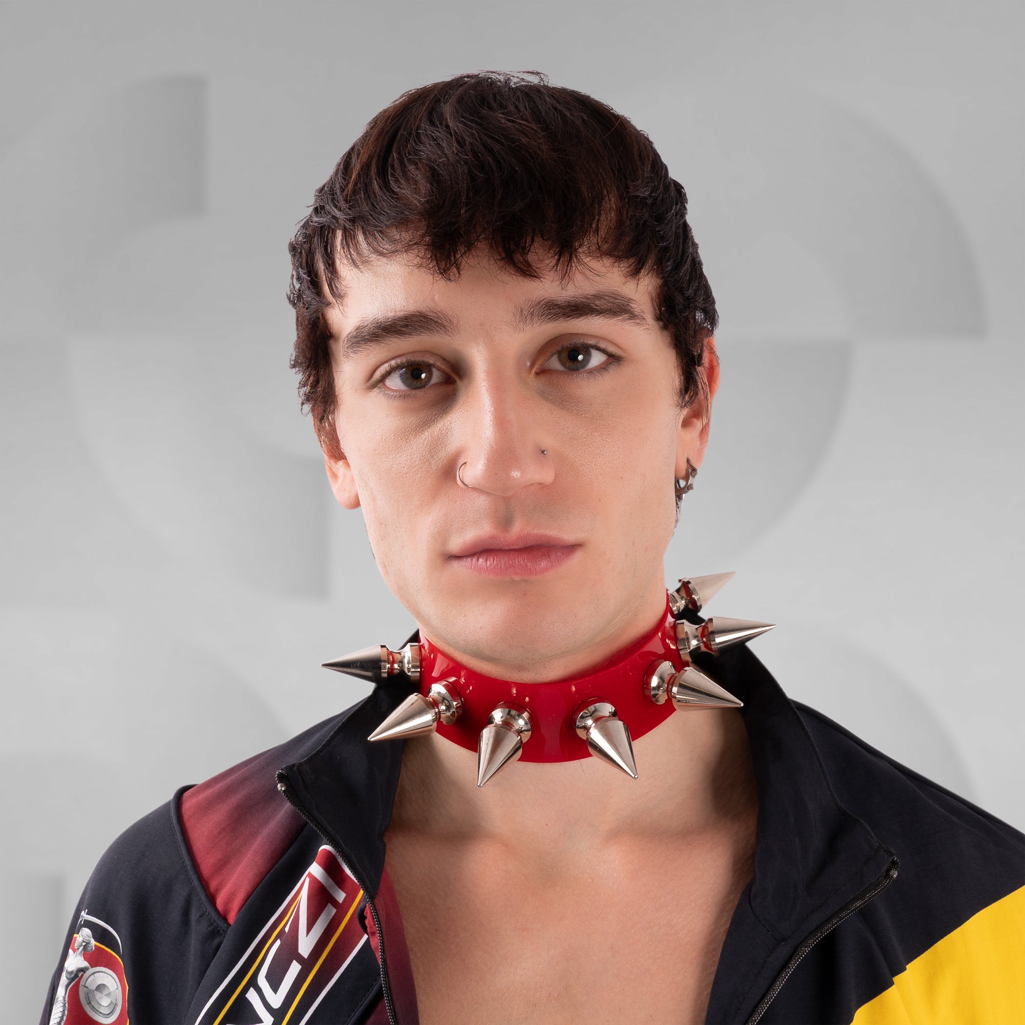 Person wearing a red spiked collar against a gray background