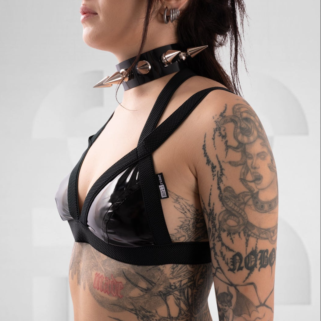 Person wearing a black latex outfit with straps on a white background